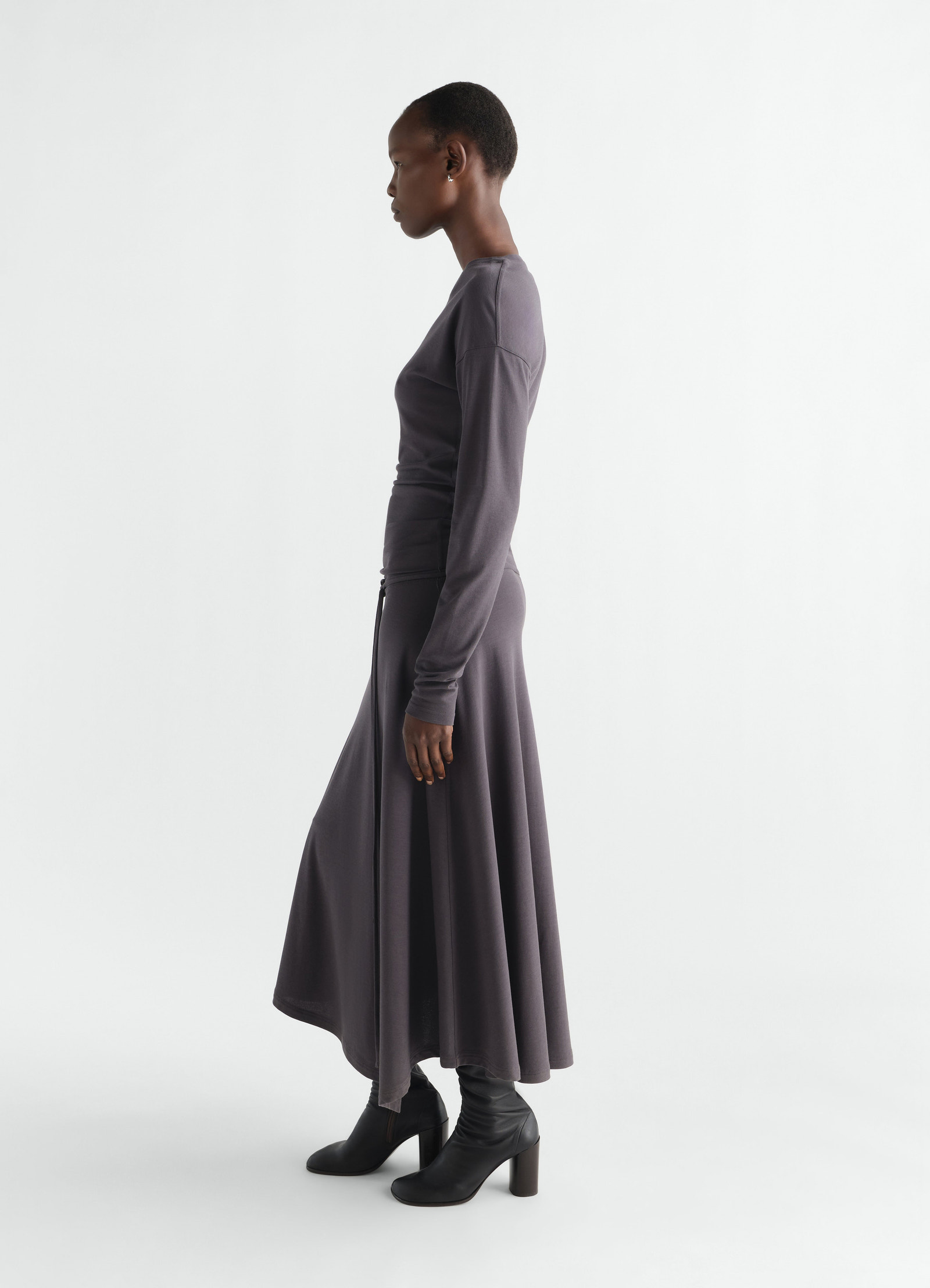 Fluid long-sleeve purple jersey crepe dress by lemaire worn by model side view with black boots