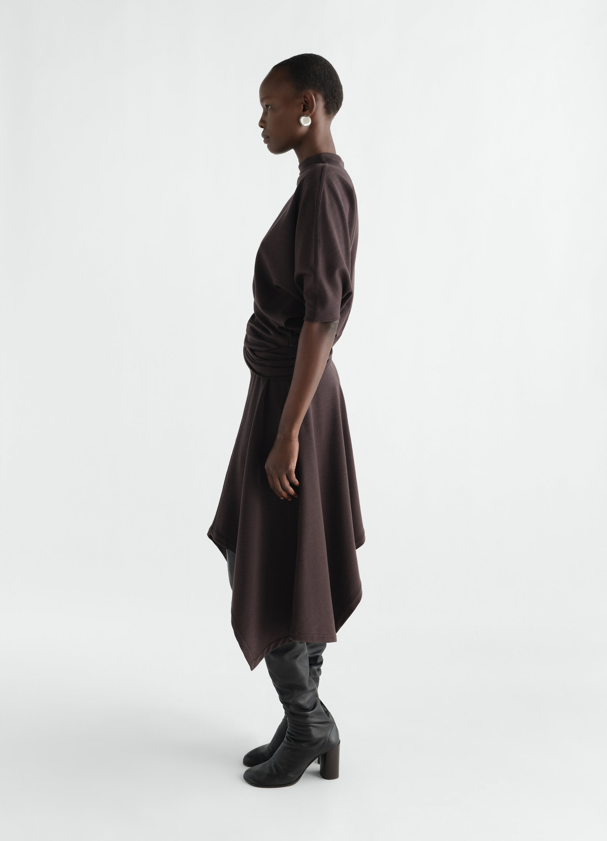 Twisted wool-blend interlock jersey dress in dark brown by lemaire worn by model side view with black boots