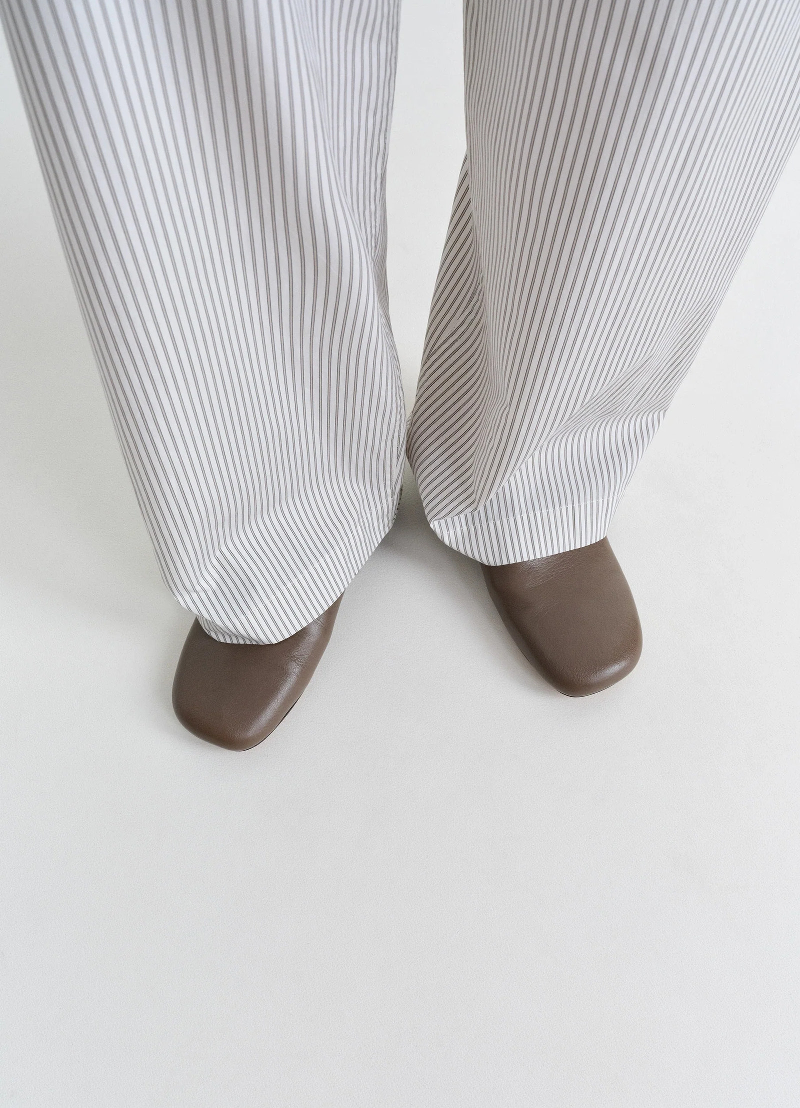 Lemaire slippers in shiny buffalo leather, model shot, top down view square toe design