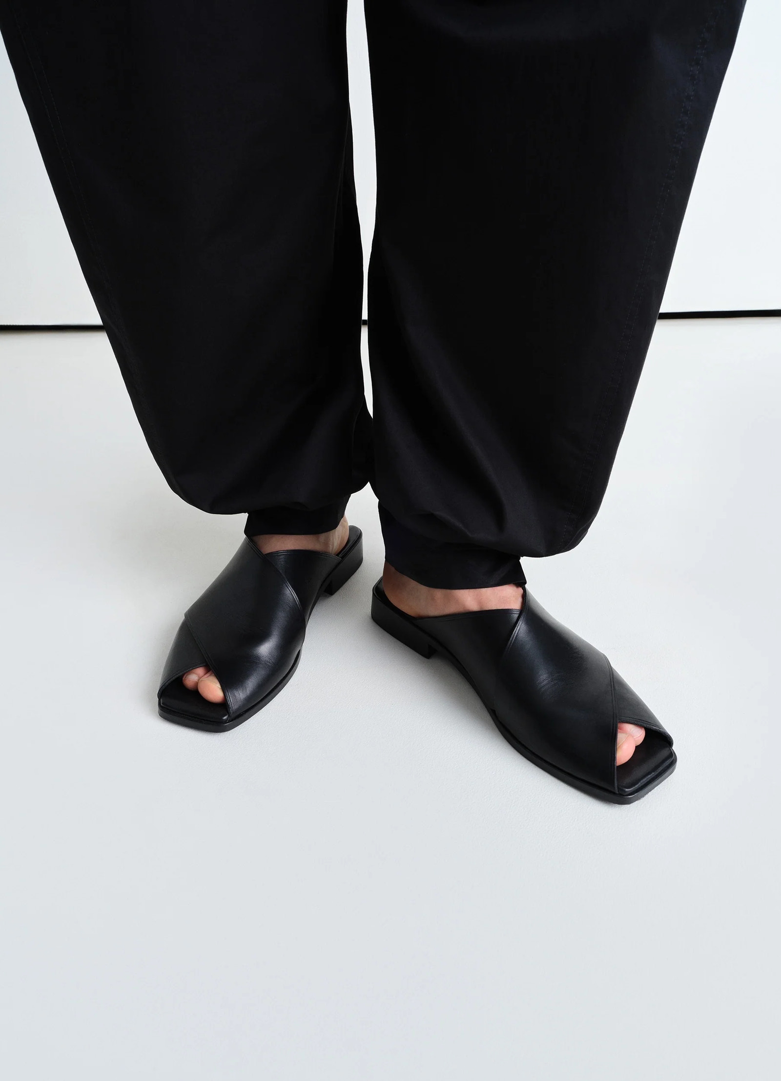 Lemaire cross flat sandals in soft shiny vegetable nappa, model shot, low angle front view open toe overlapping straps