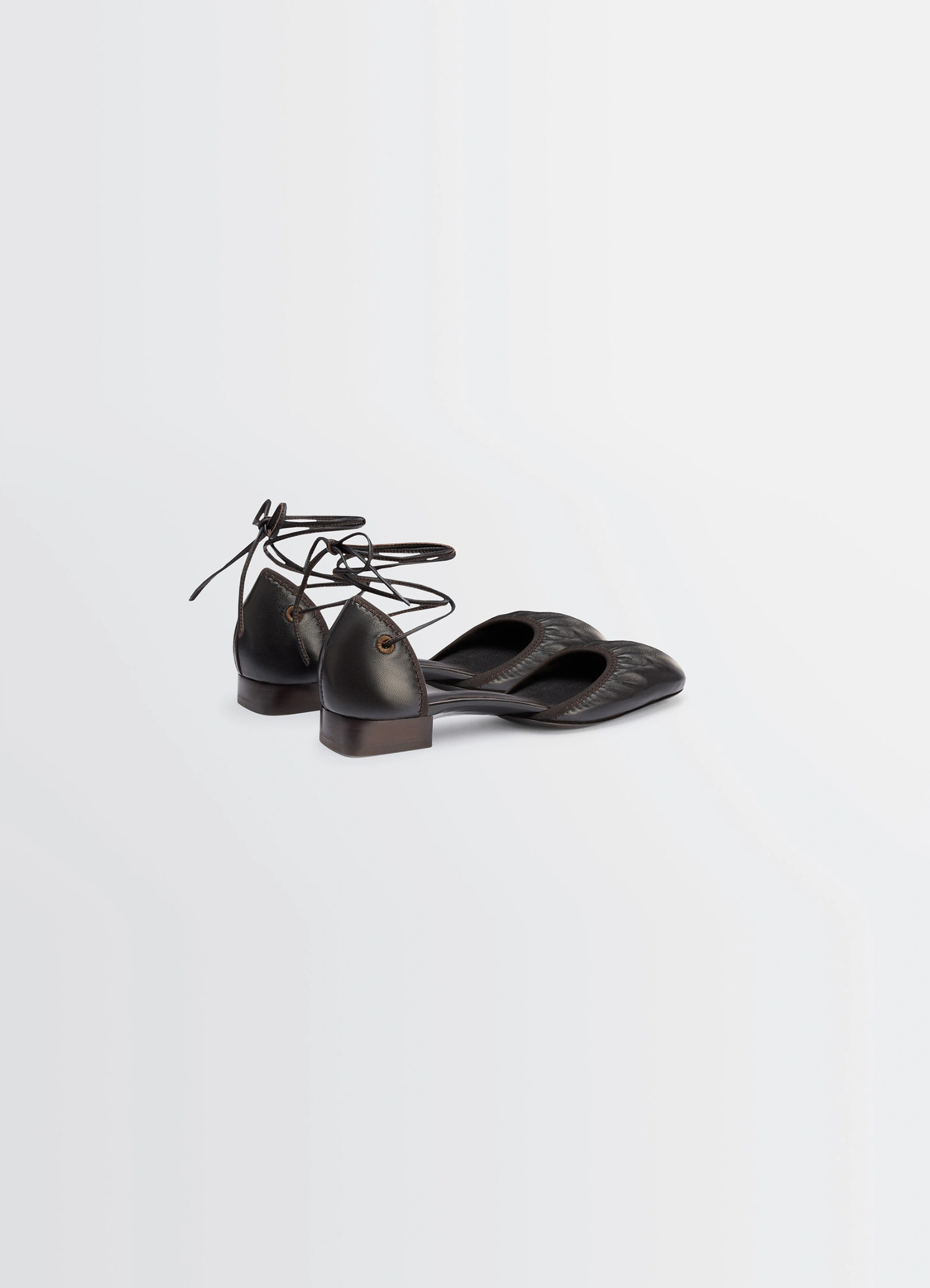 Micro ballerina flat in black supple leather, product shot, rear three-quarter view lace-up back design