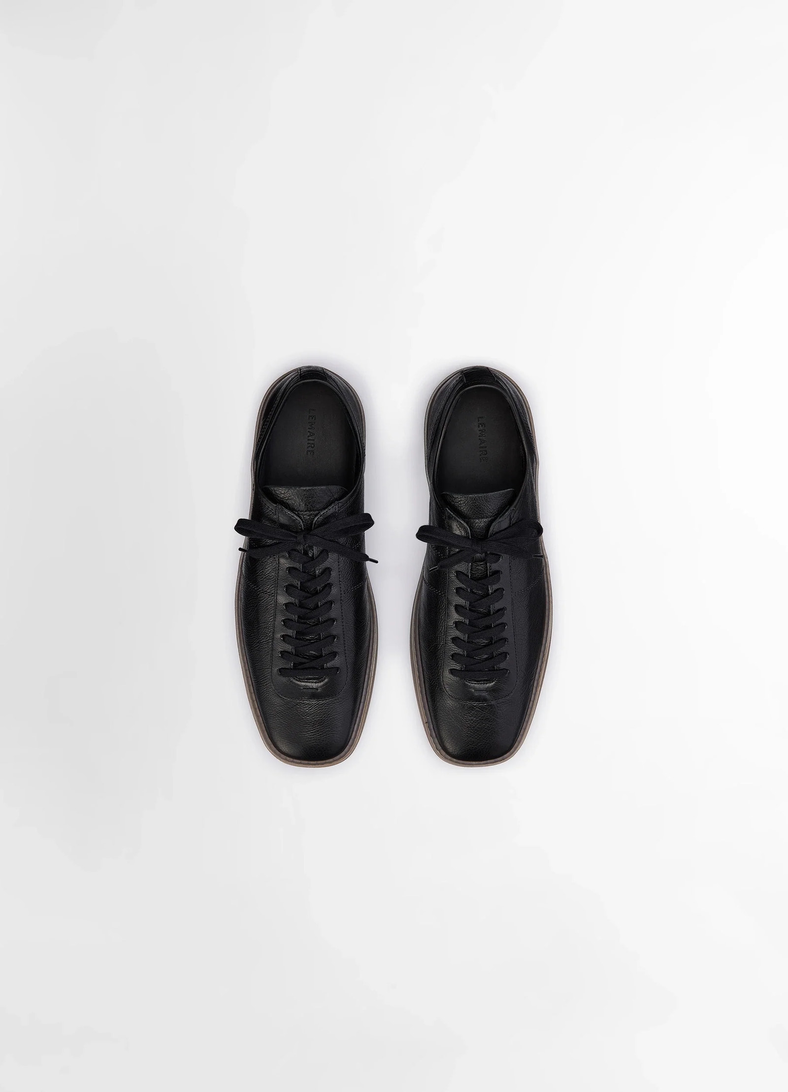 Linoleum laced up trainers in black smooth cow leather, product shot, overhead view parallel lace alignment