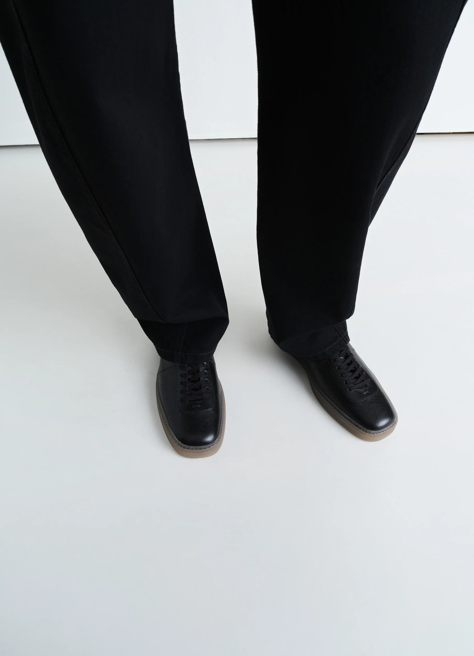 Linoleum laced up sneakers in black smooth soft cow leather, model shot, top view natural leather texture