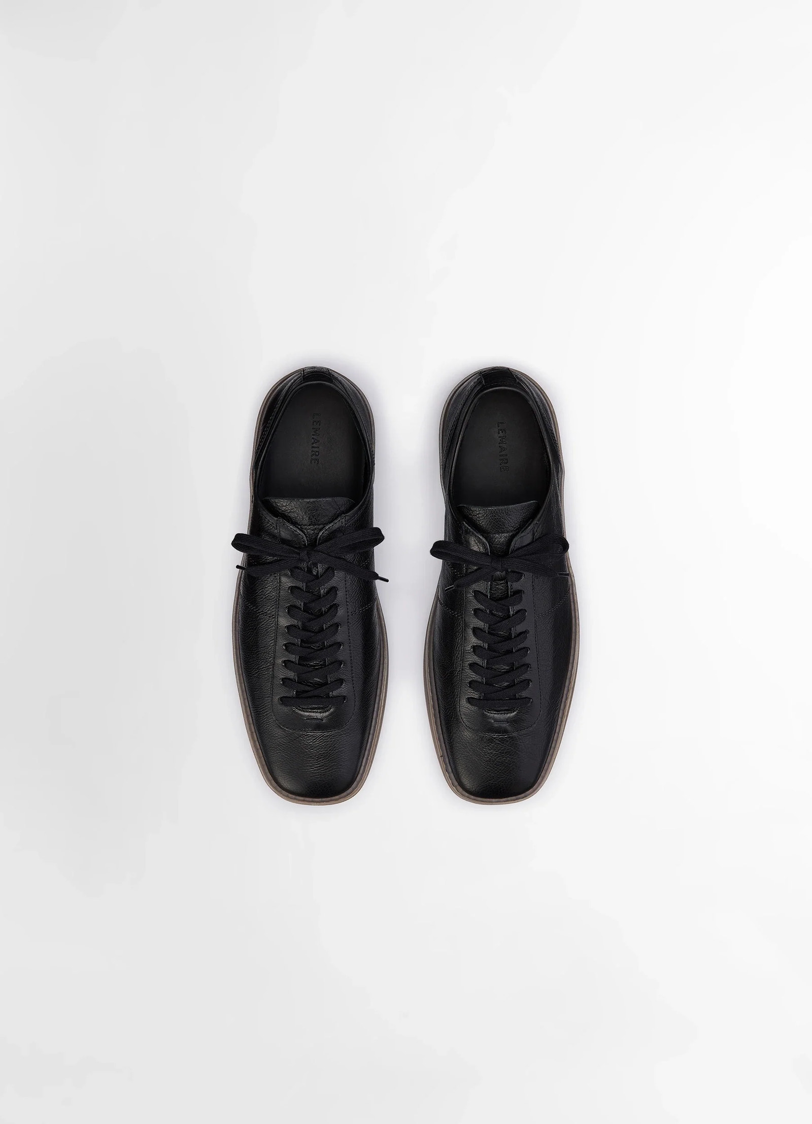Linoleum laced up sneakers in black smooth soft cow leather, product shot, overhead view symmetrical lace pattern