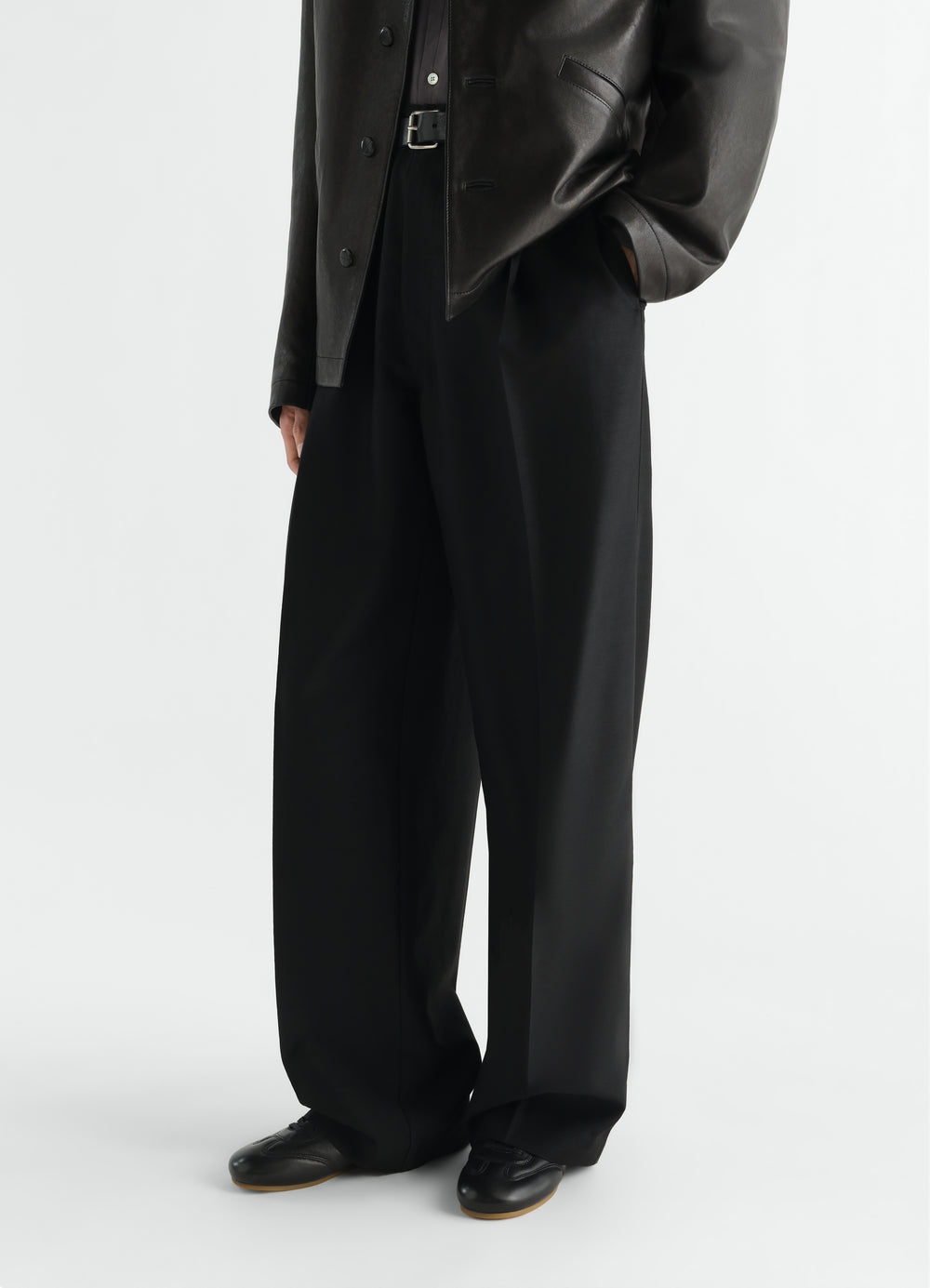 Soft black leather runner shoes worn by model with wide black trousers LEMAIRE styled look