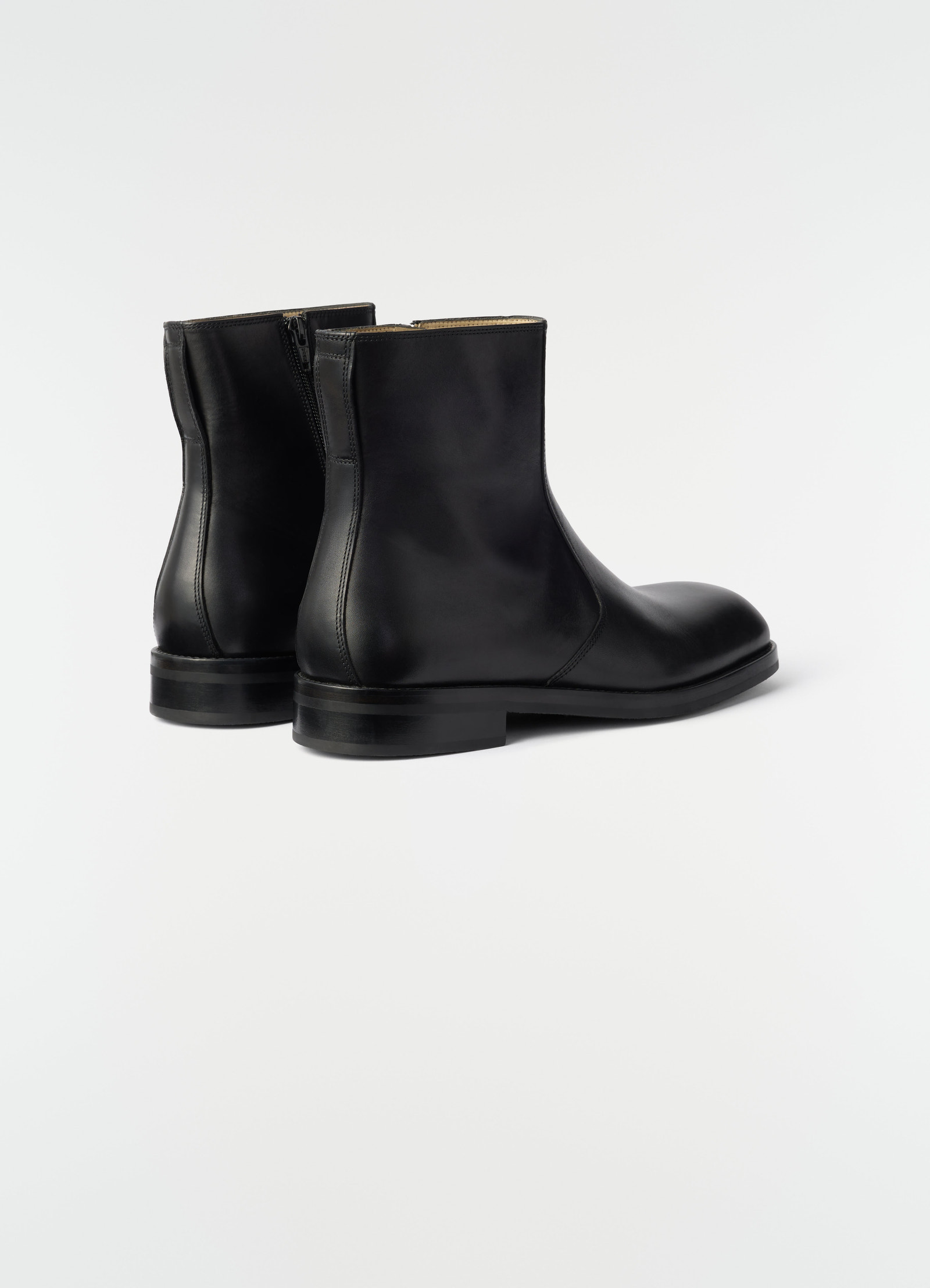 Zipped black shiny leather ankle boots by lemaire shown from rear side on plain white background