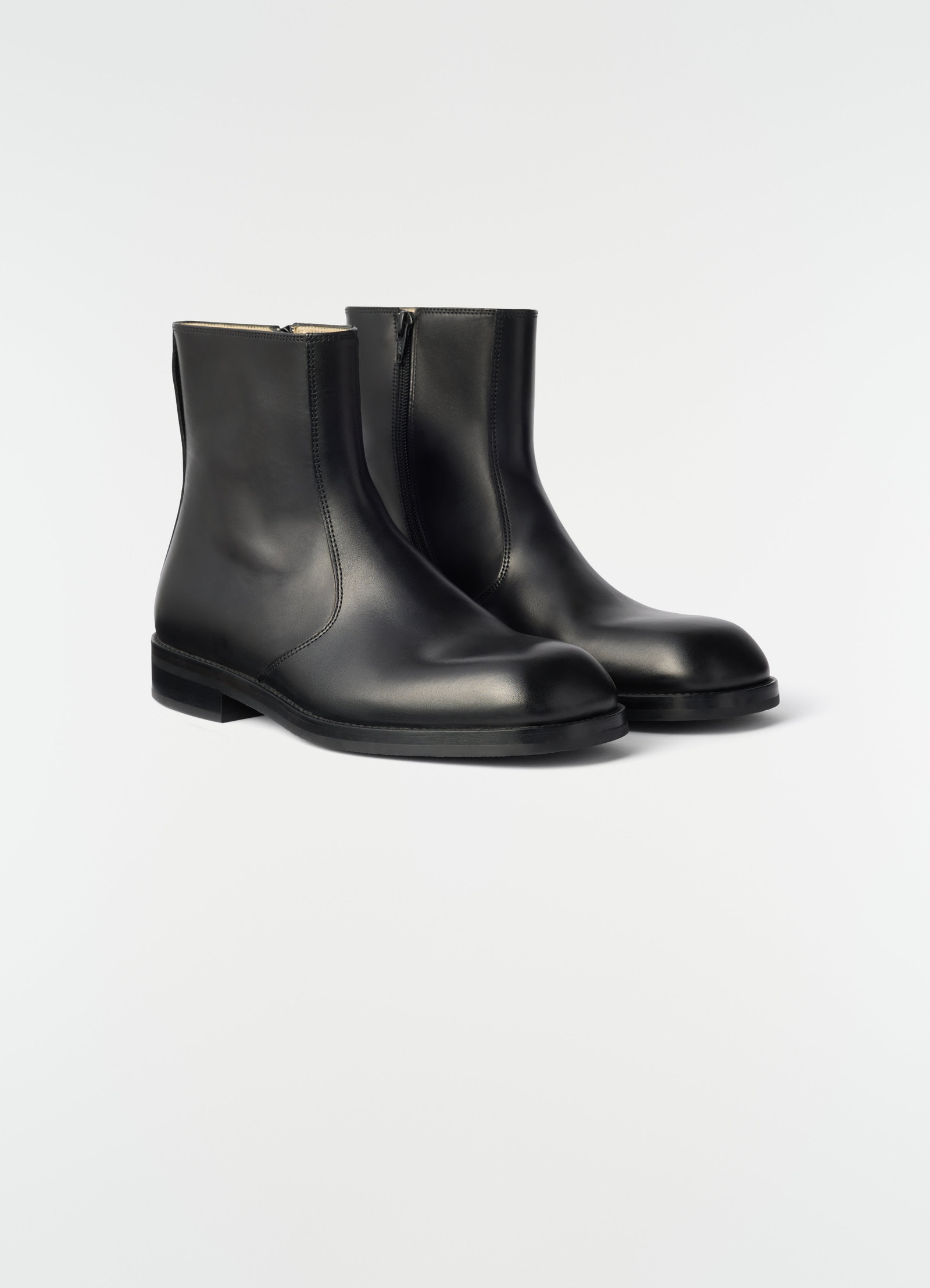 Zipped black shiny leather ankle boots by lemaire angled view on plain white background