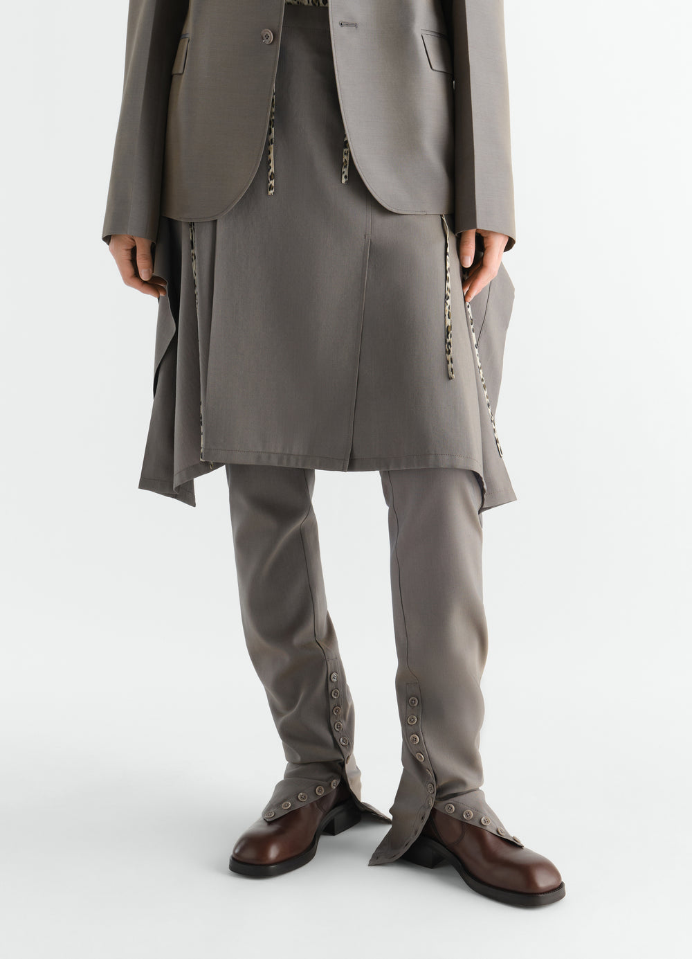 STIEFELETTEN MIT REISSVERSCHLUSS AUS GLÄNZENDEM LEDER, in Braun, von einem Model getragen, Reißverschluss sichtbar