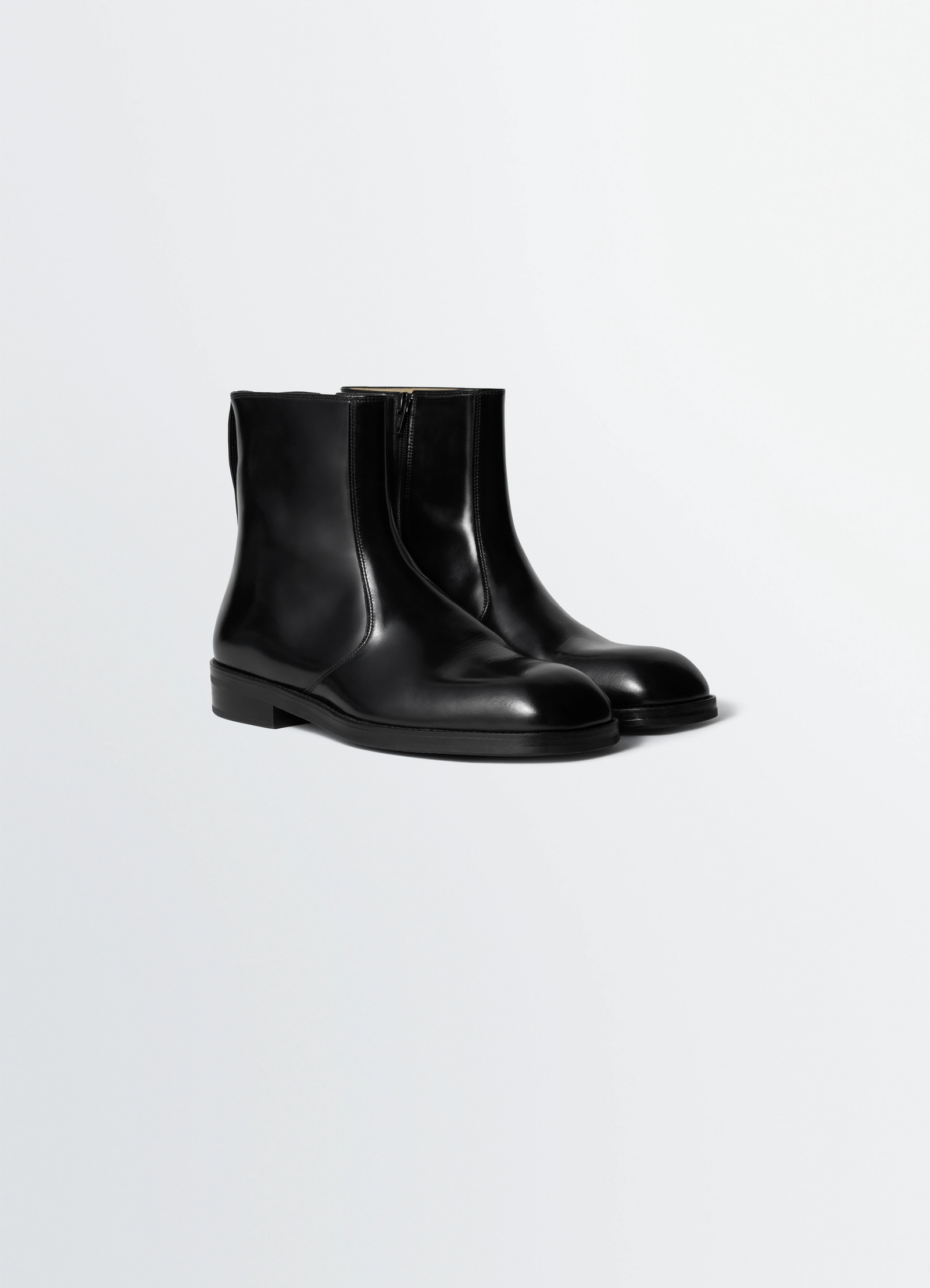Zipped boots in leather in black calf leather, product shot, three-quarter view sleek minimalist design