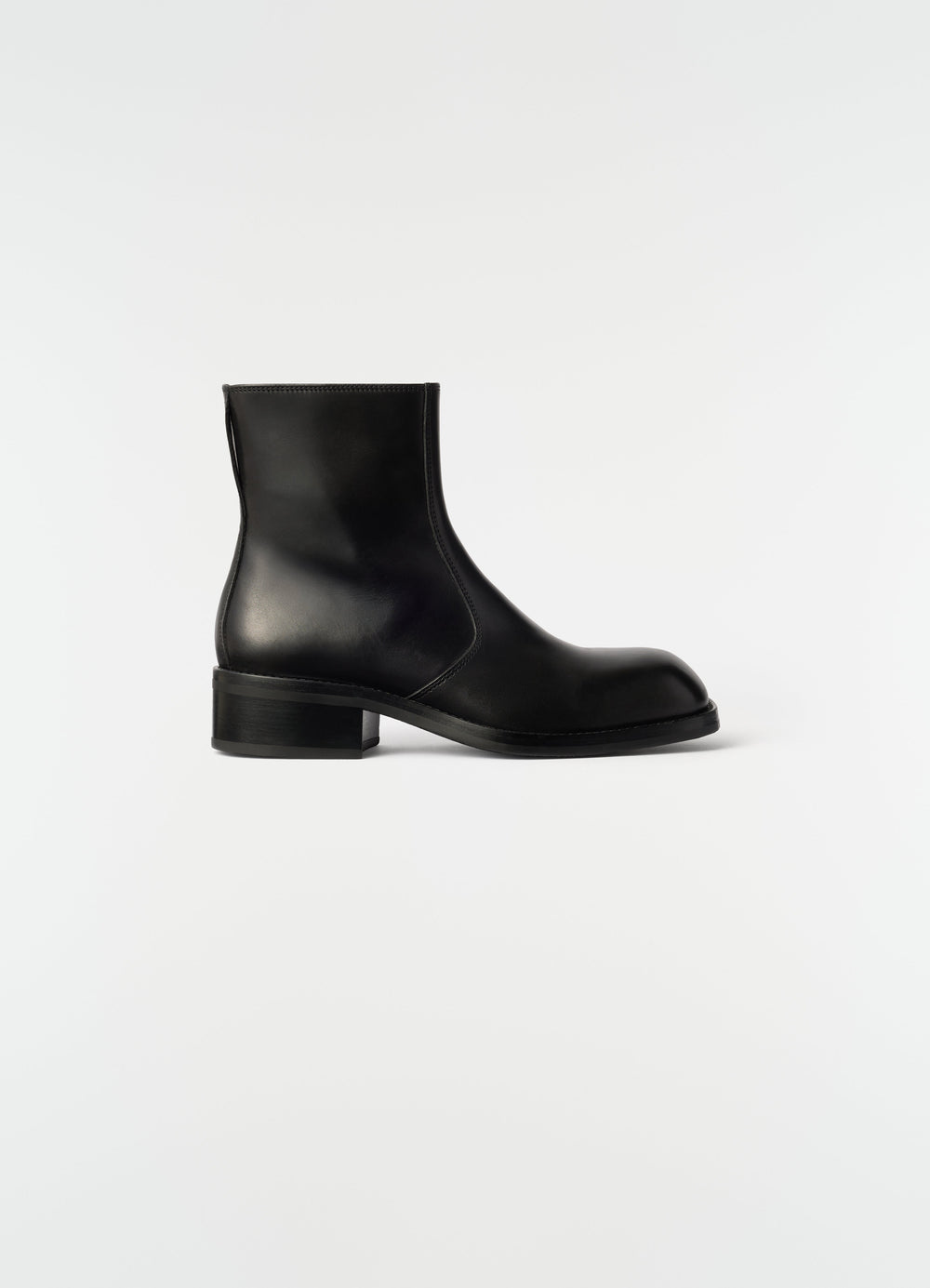 Zipped ankle boots in shiny black leather by LEMAIRE side view on plain white background