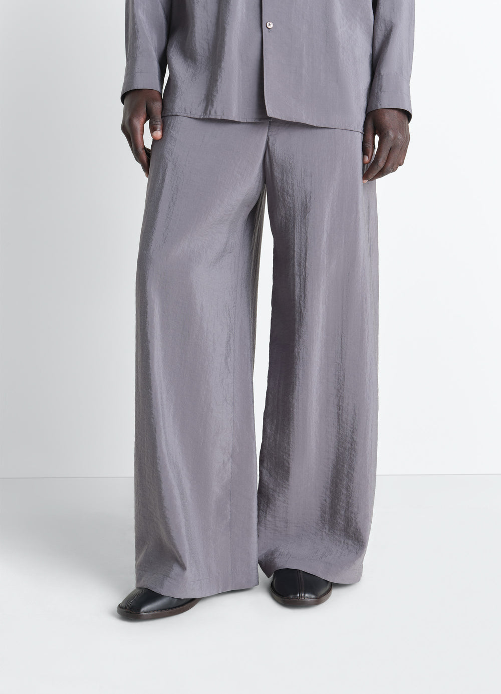 Lemaire Flat Piped Slippers in Black Nappa Lamb Leather, model shot, bottom view shiny texture, under pants