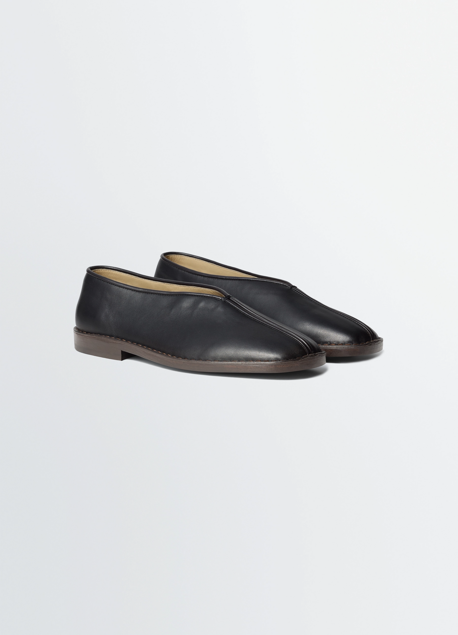 Lemaire flat piped slippers in black lwg gold-certified nappa leat, product shot, three-quarter front a smooth leather upper