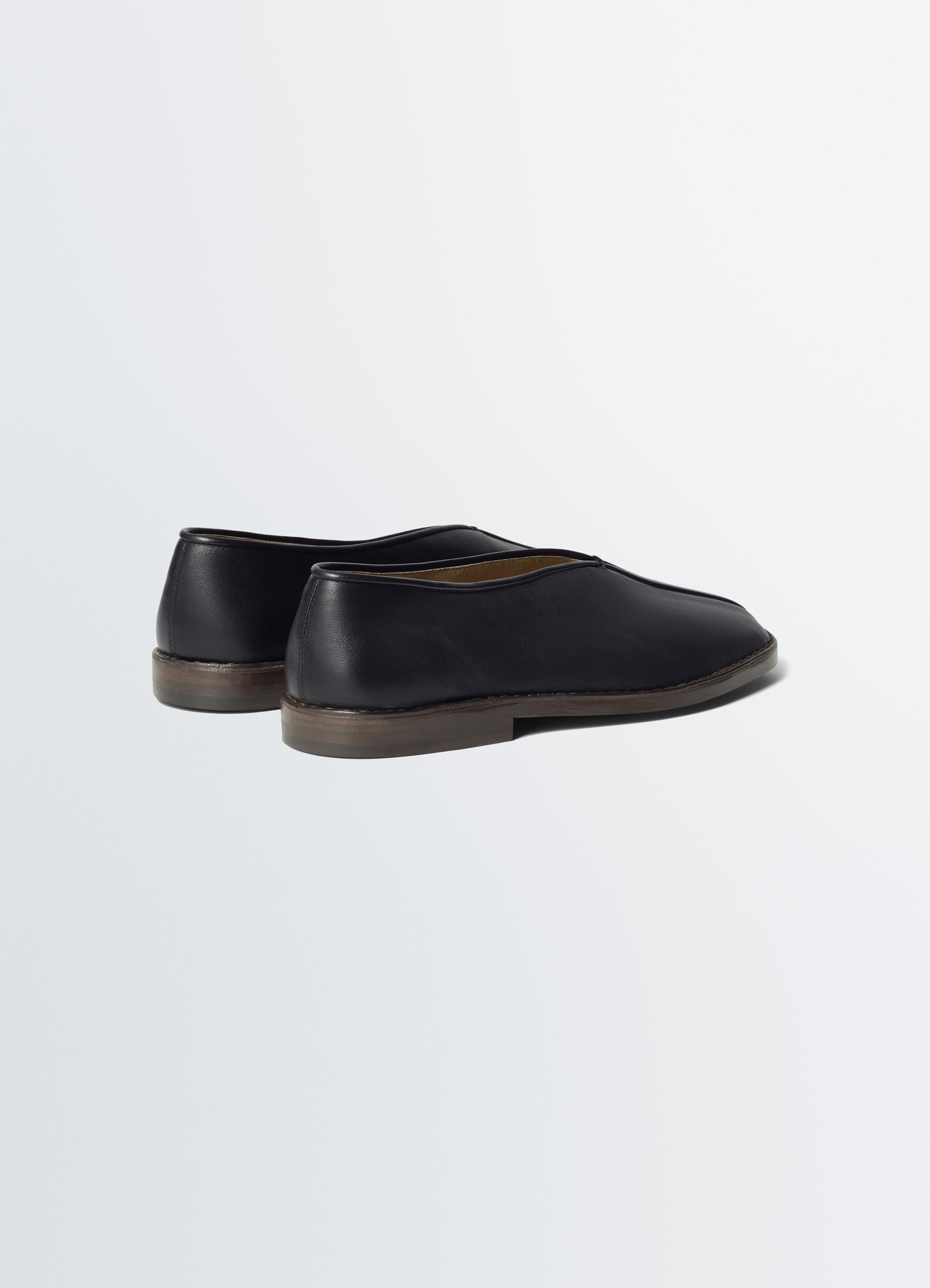 Lemaire flat piped slippers in black nappa lamb leather, product shot, rear view elevated heel, elegant finish