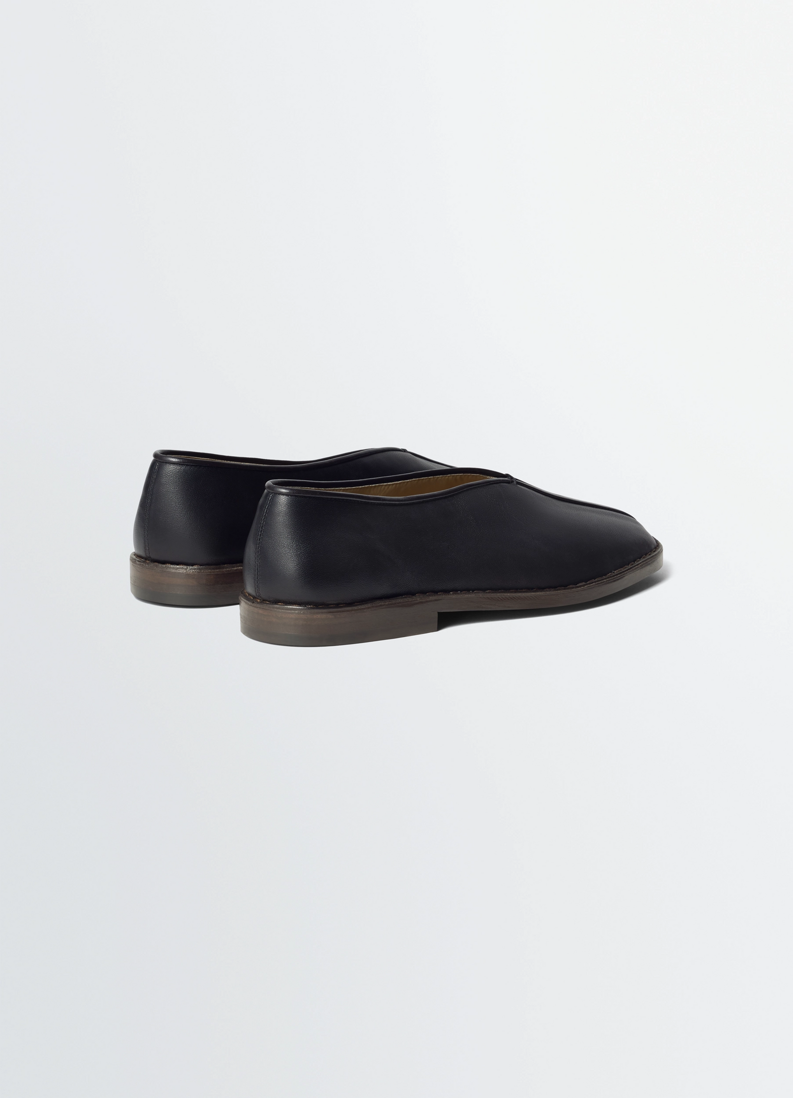 Lemaire flat piped slippers in black lwg gold-certified nappa leat, product shot, rear three-quarter an low heel with seamles