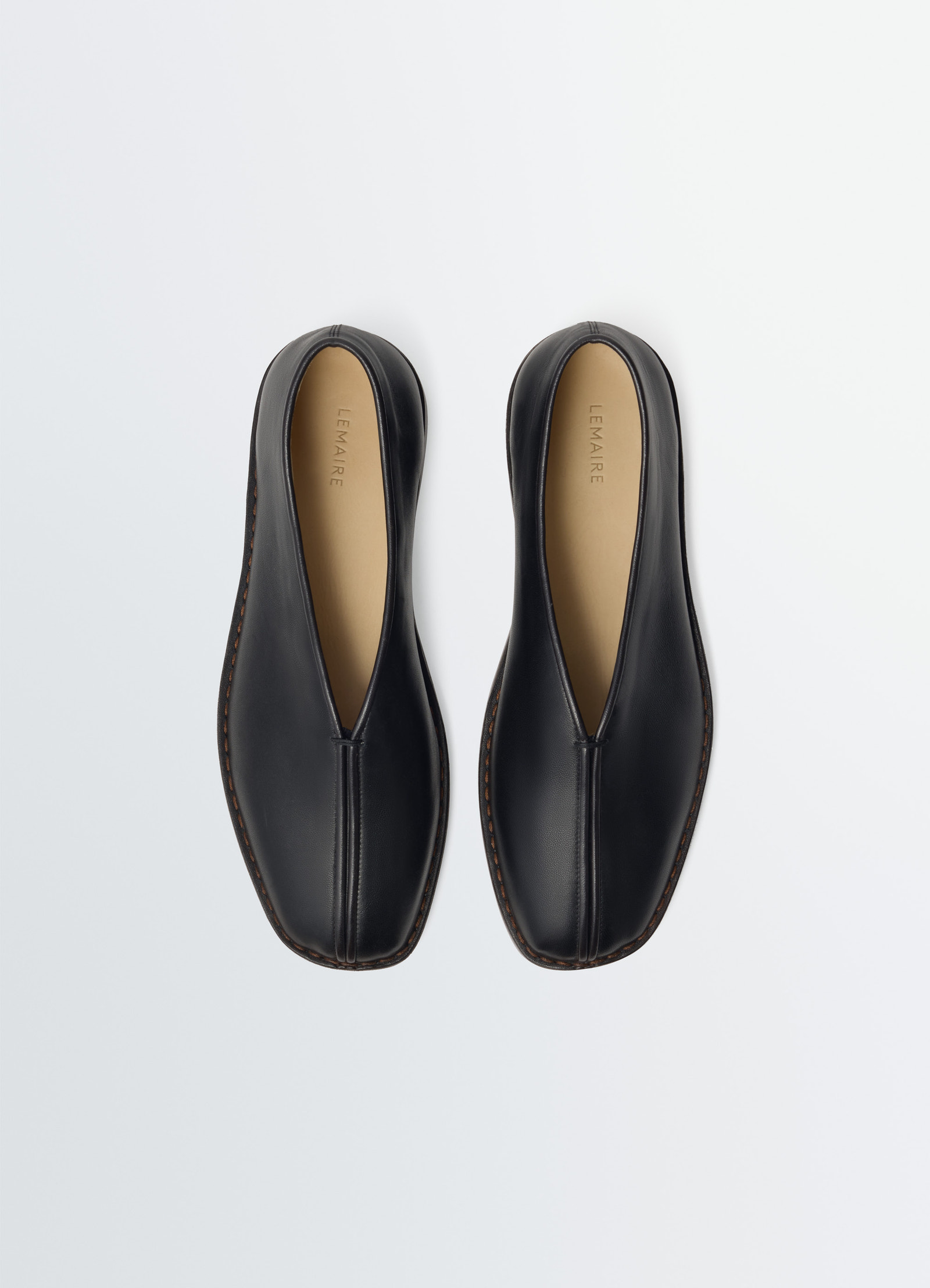Lemaire flat piped slippers in black nappa lamb leather, product shot, top down view symmetrical sleek design