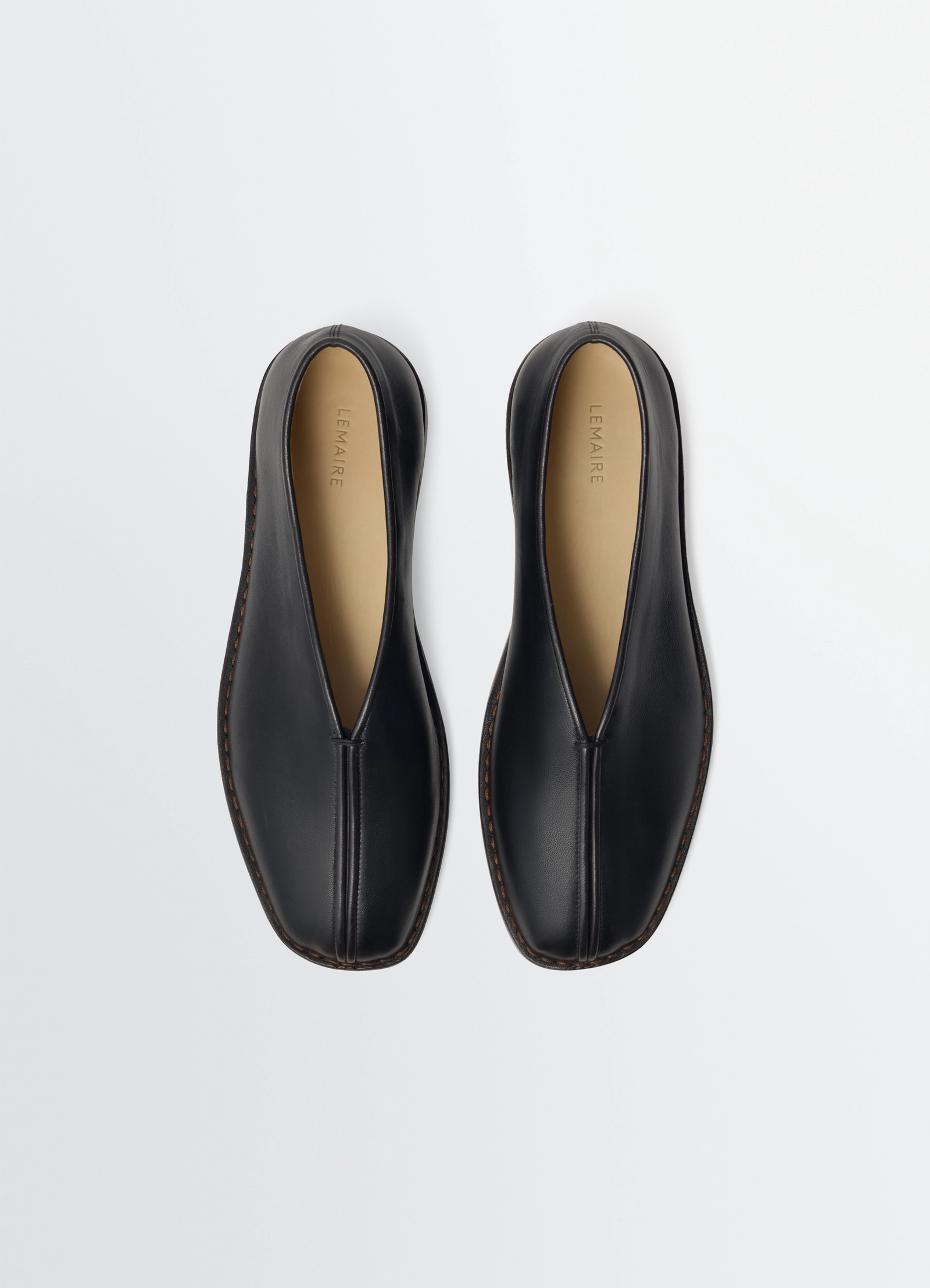 Lemaire flat piped slippers in black lwg gold-certified nappa leat, product shot, top-down view central seam detail