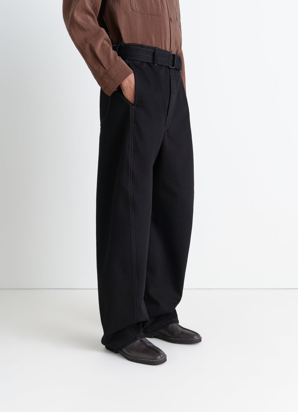Black leather piped crepe slippers LEMAIRE worn by model side view with black wide trousers and brown shirt