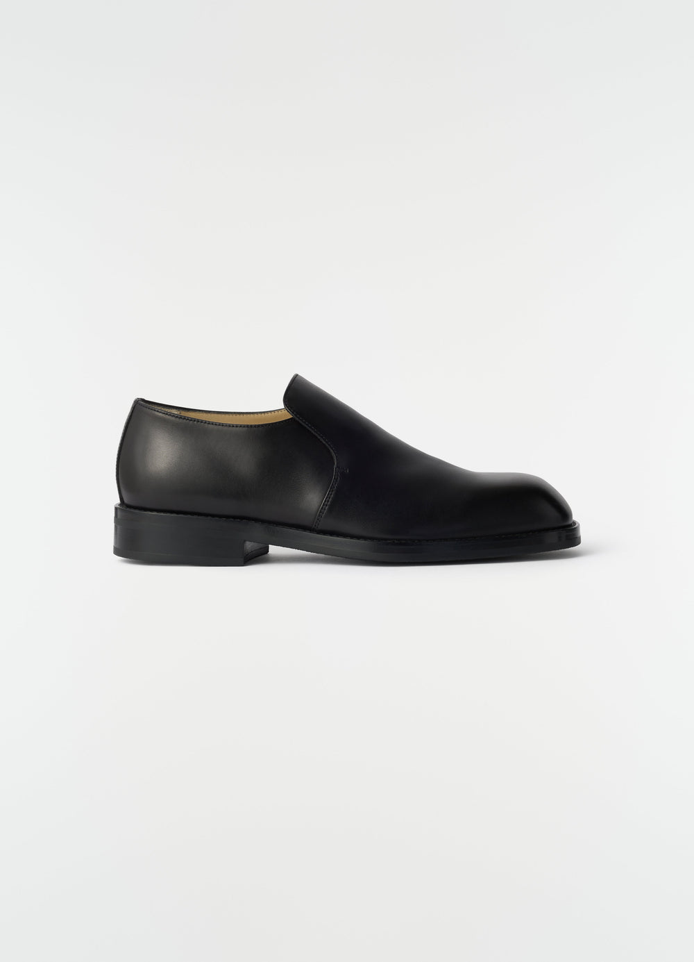 Formal black shiny leather loafers by LEMAIRE side view on plain white background