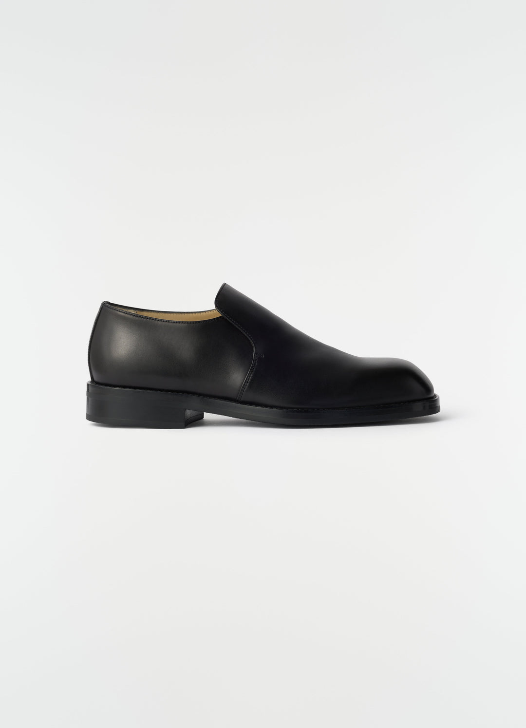 Formal black shiny leather loafers by LEMAIRE side view on plain white background