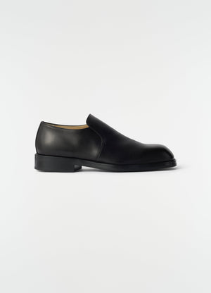 Formal black shiny leather loafers by lemaire side view on plain white background