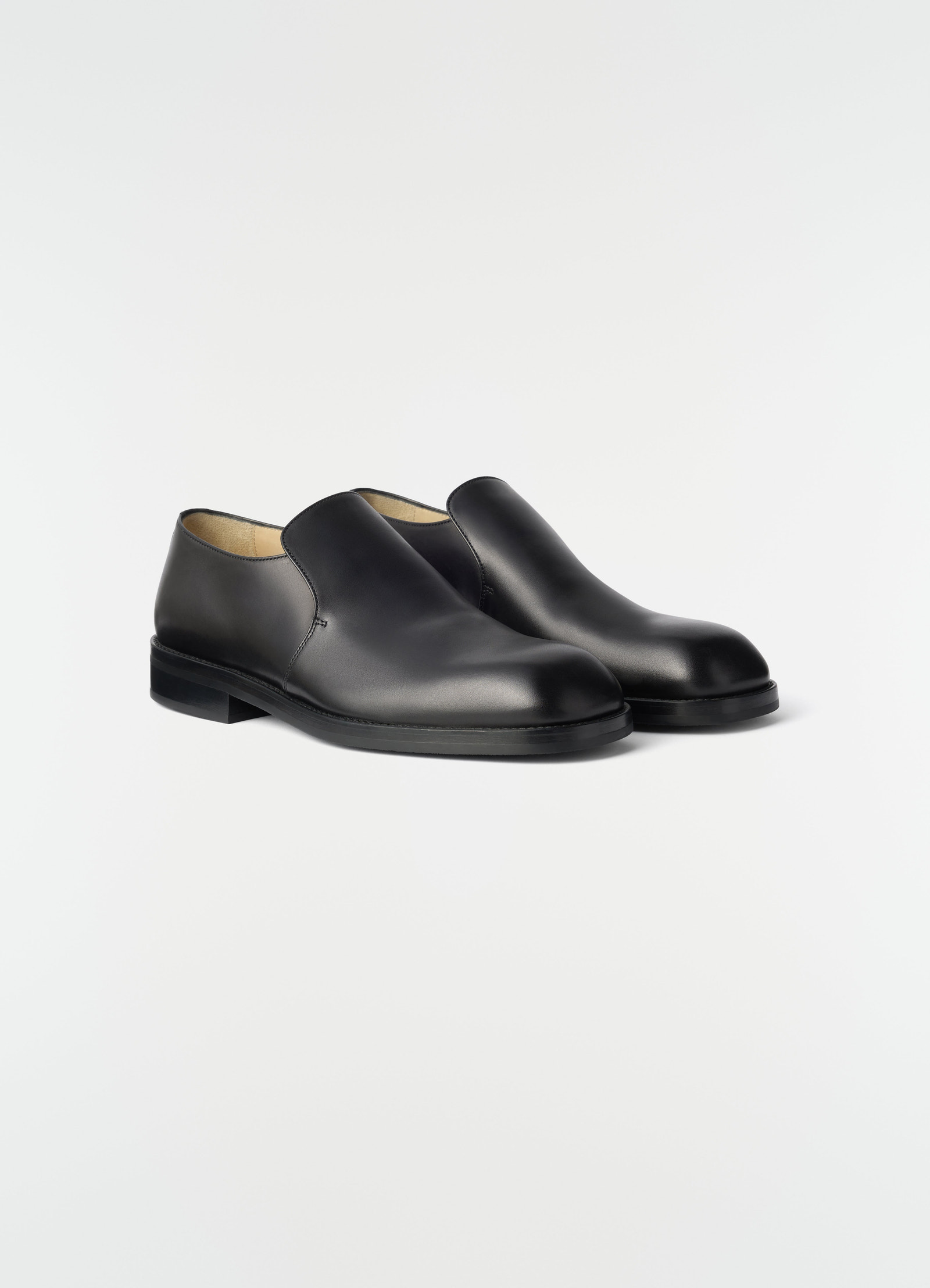 Formal black shiny leather loafers by lemaire styled on plain white background, side front view