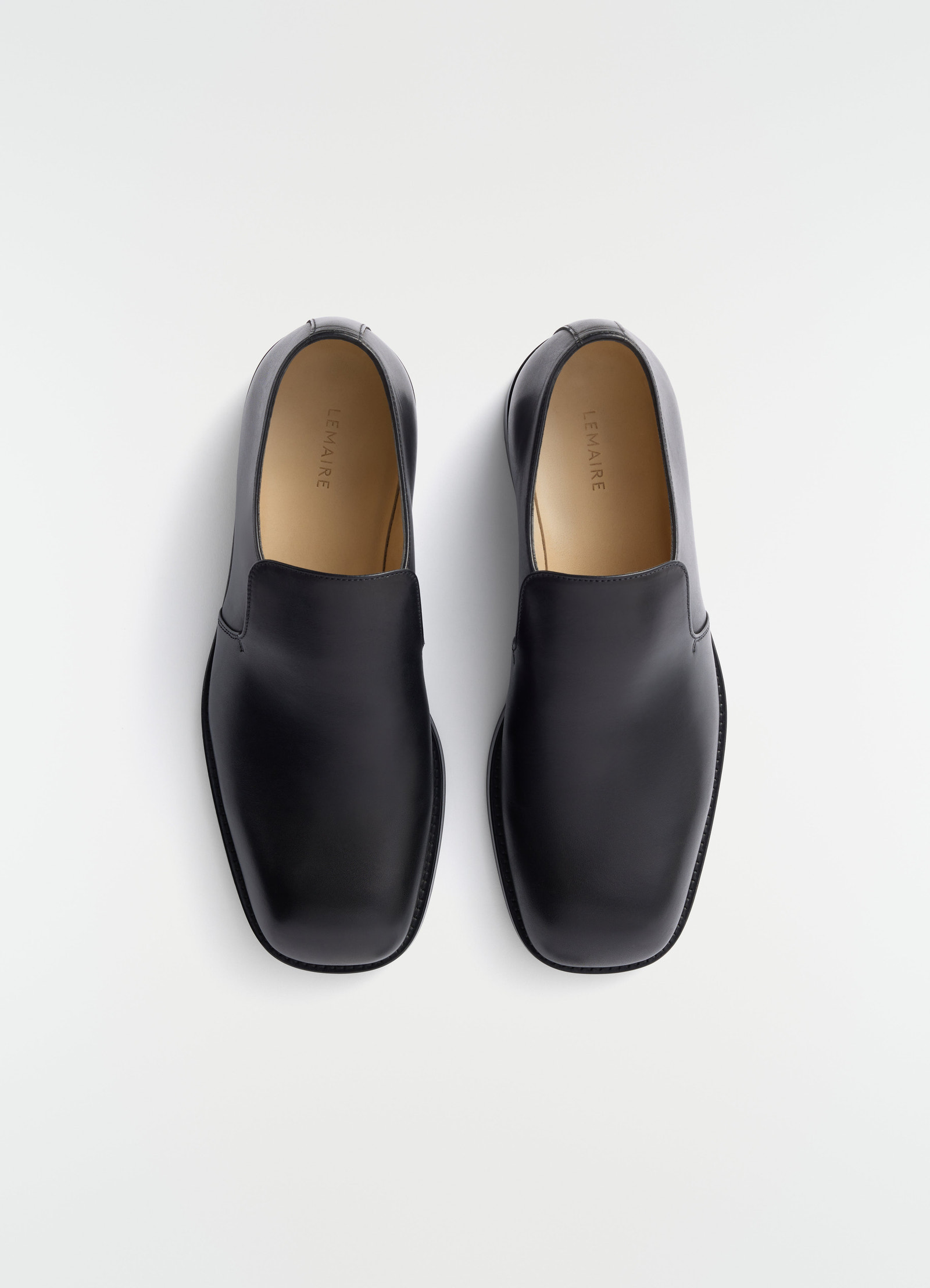 Formal black shiny leather loafers lemaire top view on plain white background