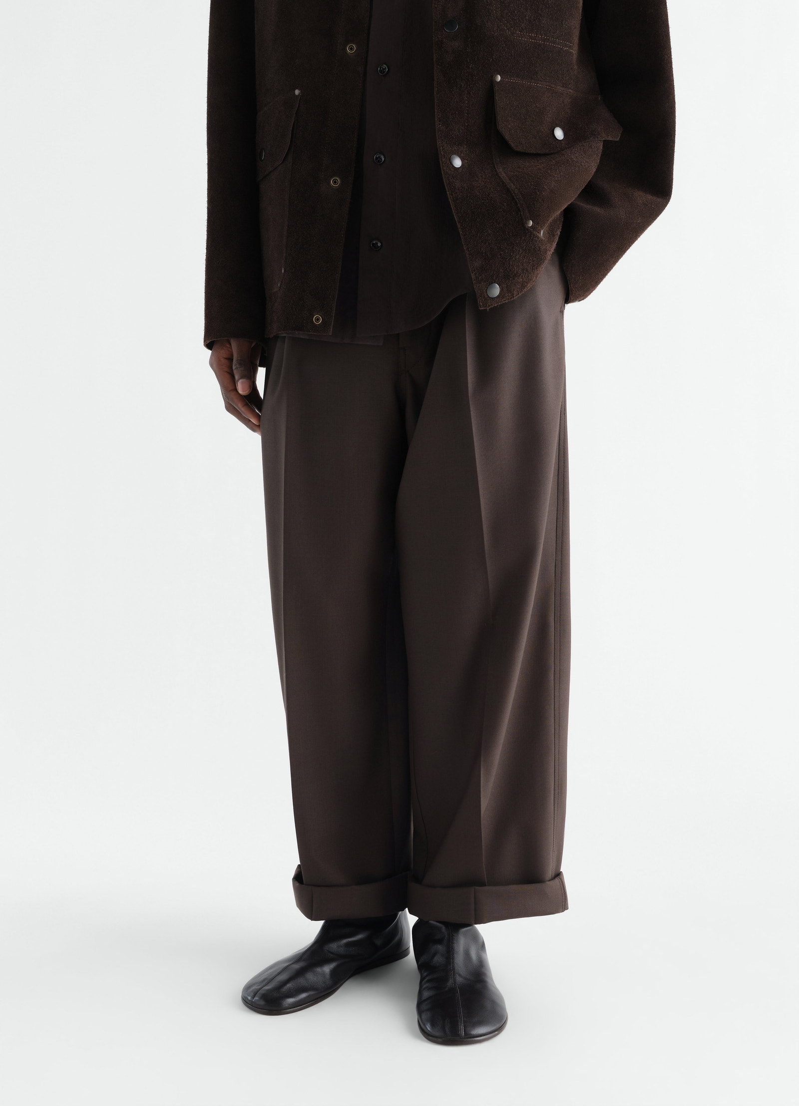 Sock ankle boots in shiny black nappa lambskin lemaire worn by a model front view with brown trousers and jacket