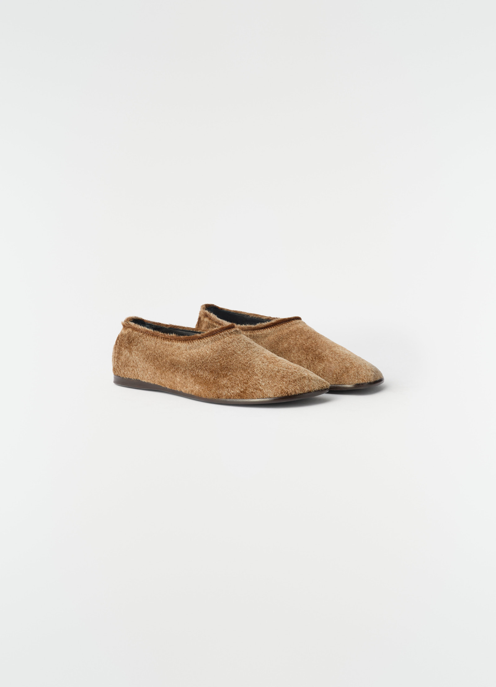 Glove slip-ons in natural brown pony-style leather with black sole by lemaire on white background, side view.