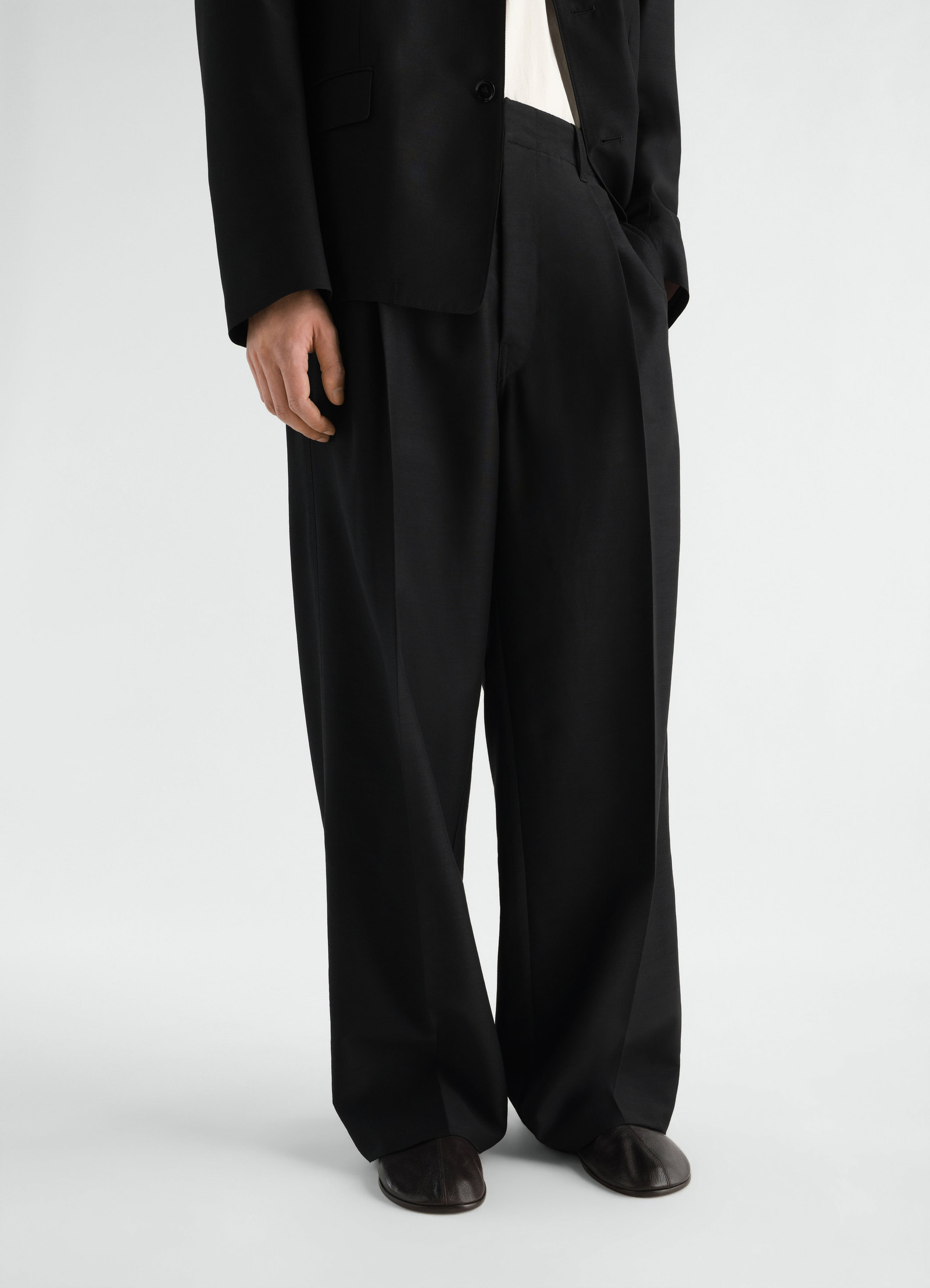 Sock slip-ons in dark brown goat leather by lemaire worn by a model front view with black wide trousers