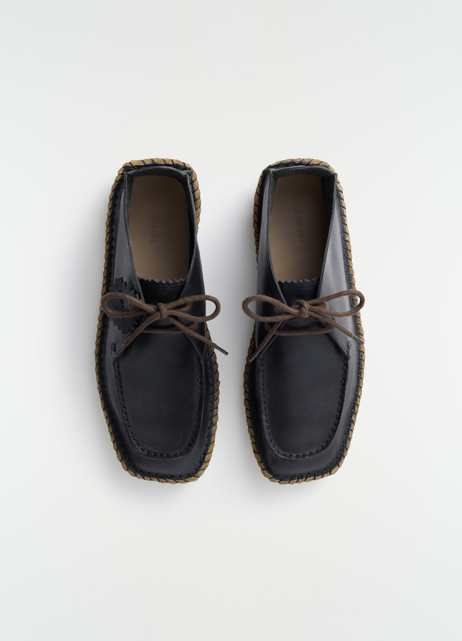 Desert moccasins in black vegetable-tanned leather with brown laces and sole by lemaire flat lay on white background