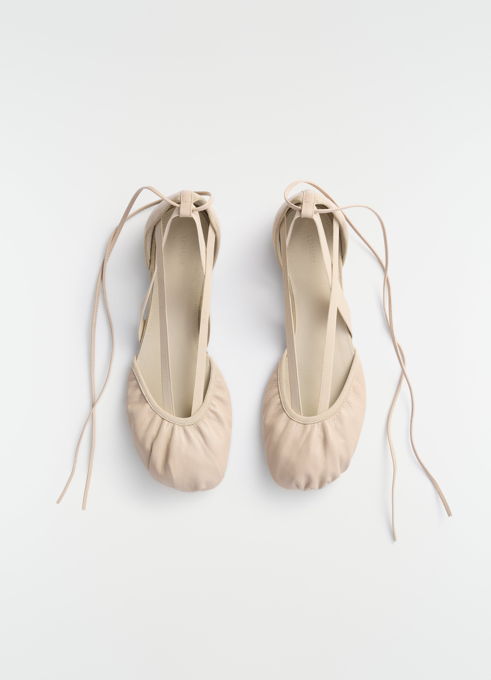 Flat pedille ballet flats in beige goat leather by lemaire with ankle ties, top view on plain white background