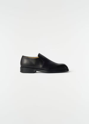 Formal black shiny leather loafers lemaire side view on plain white background