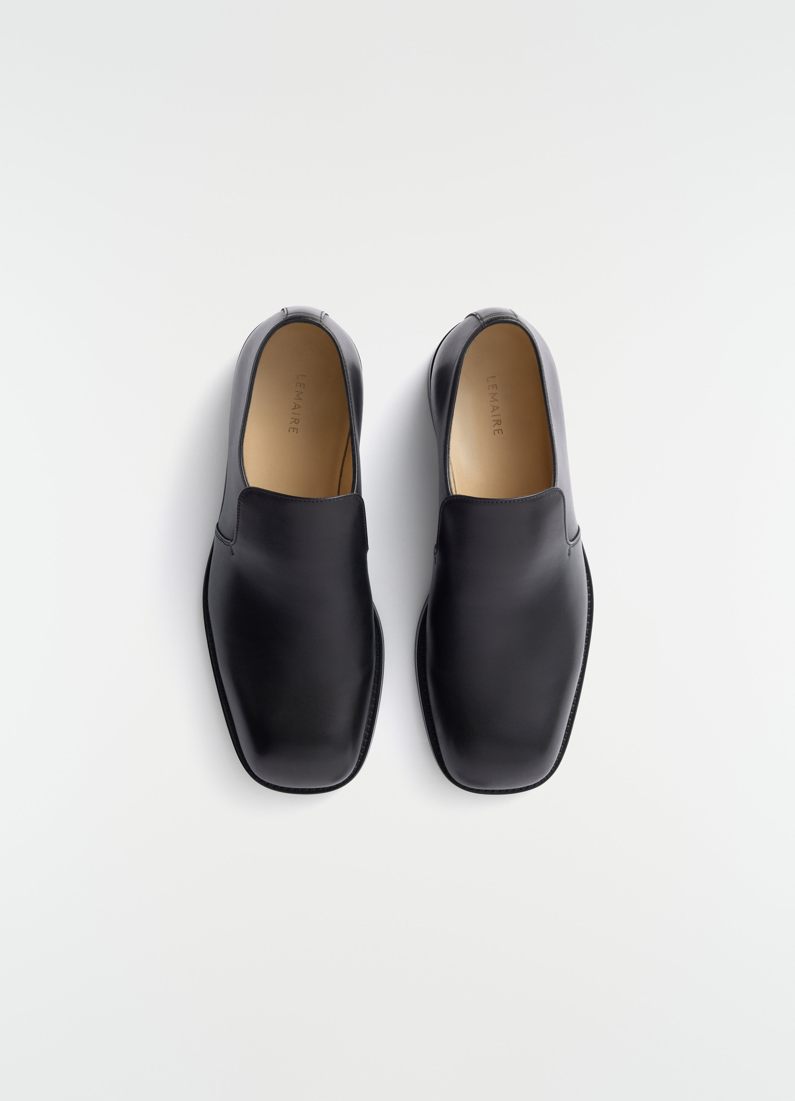 Formal black shiny leather loafers lemaire top view on plain white background