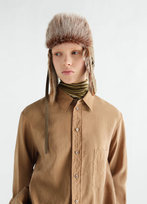 Fuzzy beige long-hair goat leather chapka by lemaire worn by model with brown shirt and green scarf