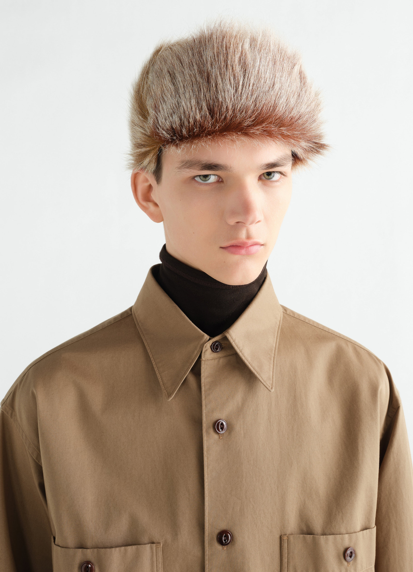 Fuzzy brown long-hair goat leather chapka worn by model with tan shirt front lemaire