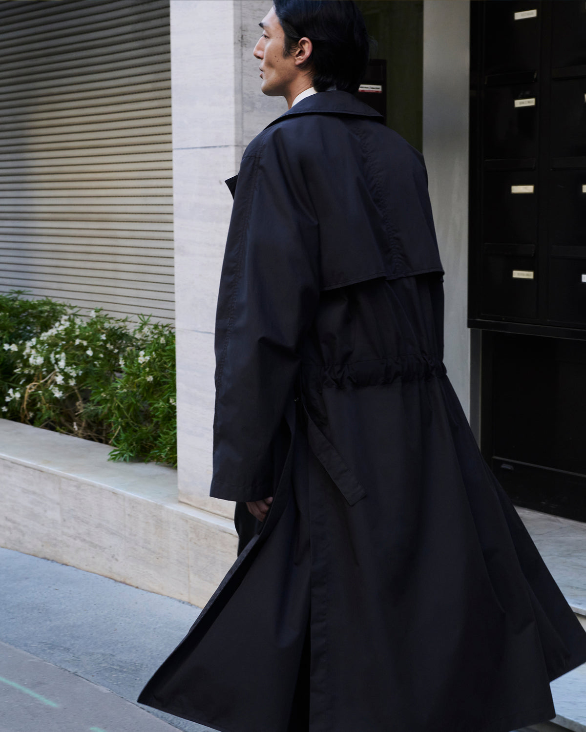 Light black water-repellent cotton gabardine trench coat by LEMAIRE worn by front and side models