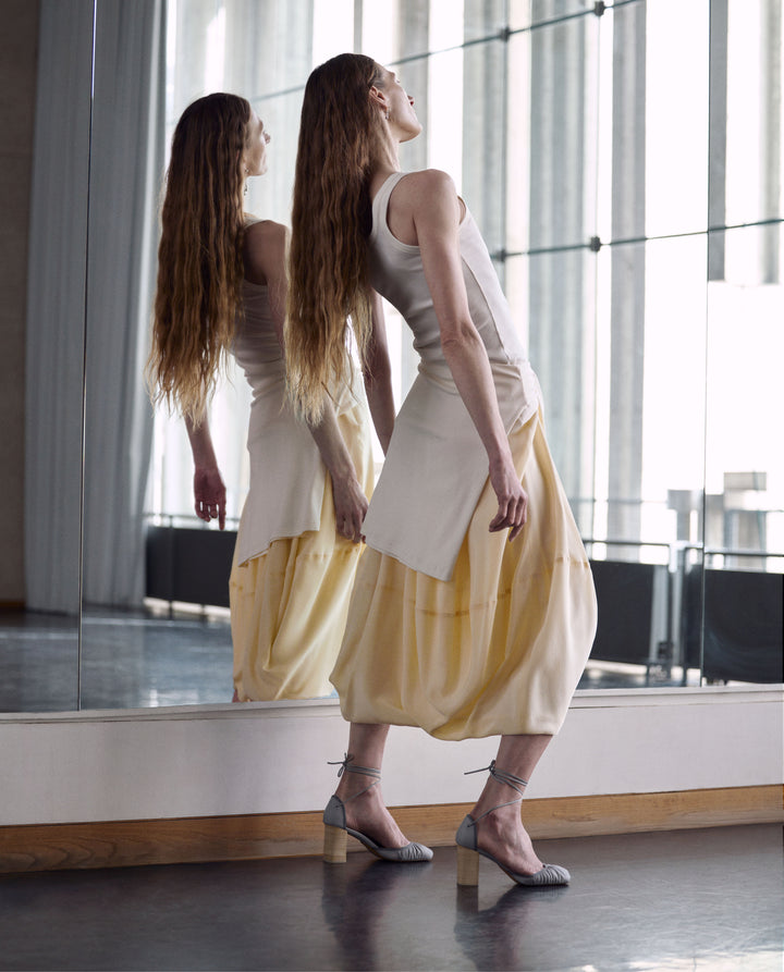 Sleeveless top and skirt in White cotton top, yellow skirt, model shot, Side view Loose fit, layered design