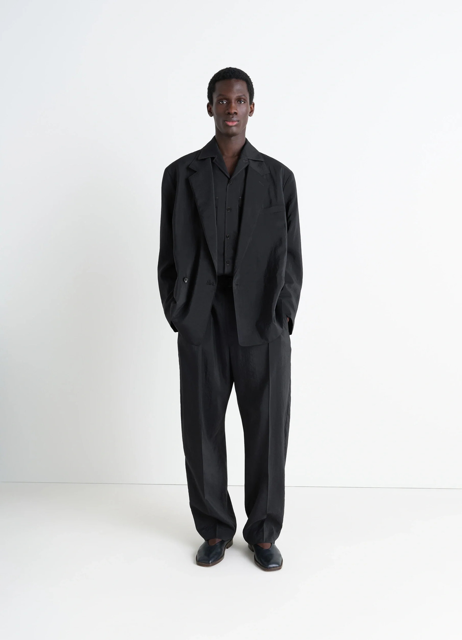 Lemaire soft double breasted jacket in black dry silk blend, model shot, full-body worn view relaxed drape