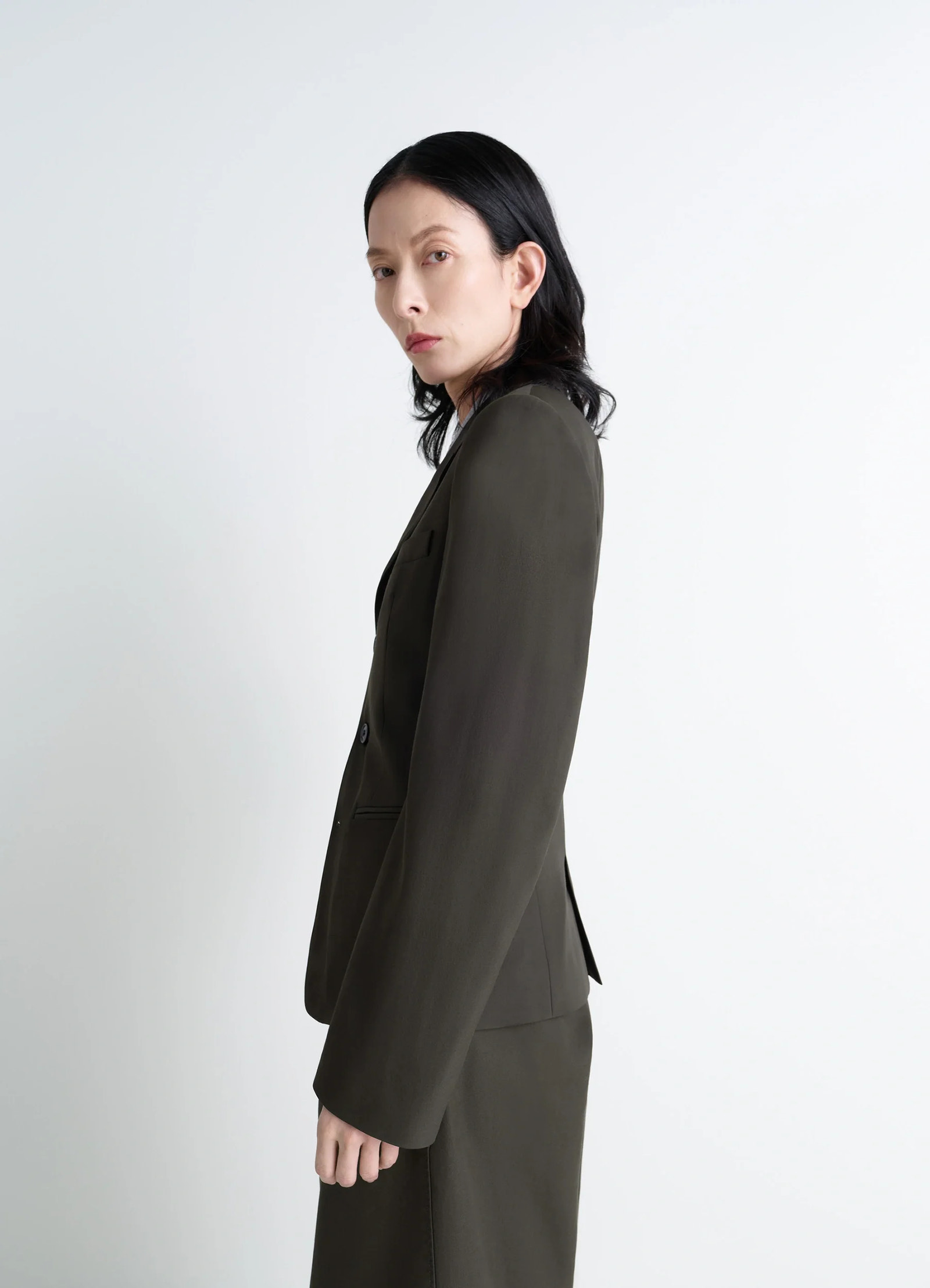 Single-breasted fitted tailored jac in wool and viscose blend gabardine, model shot, side profile view structured silhouette