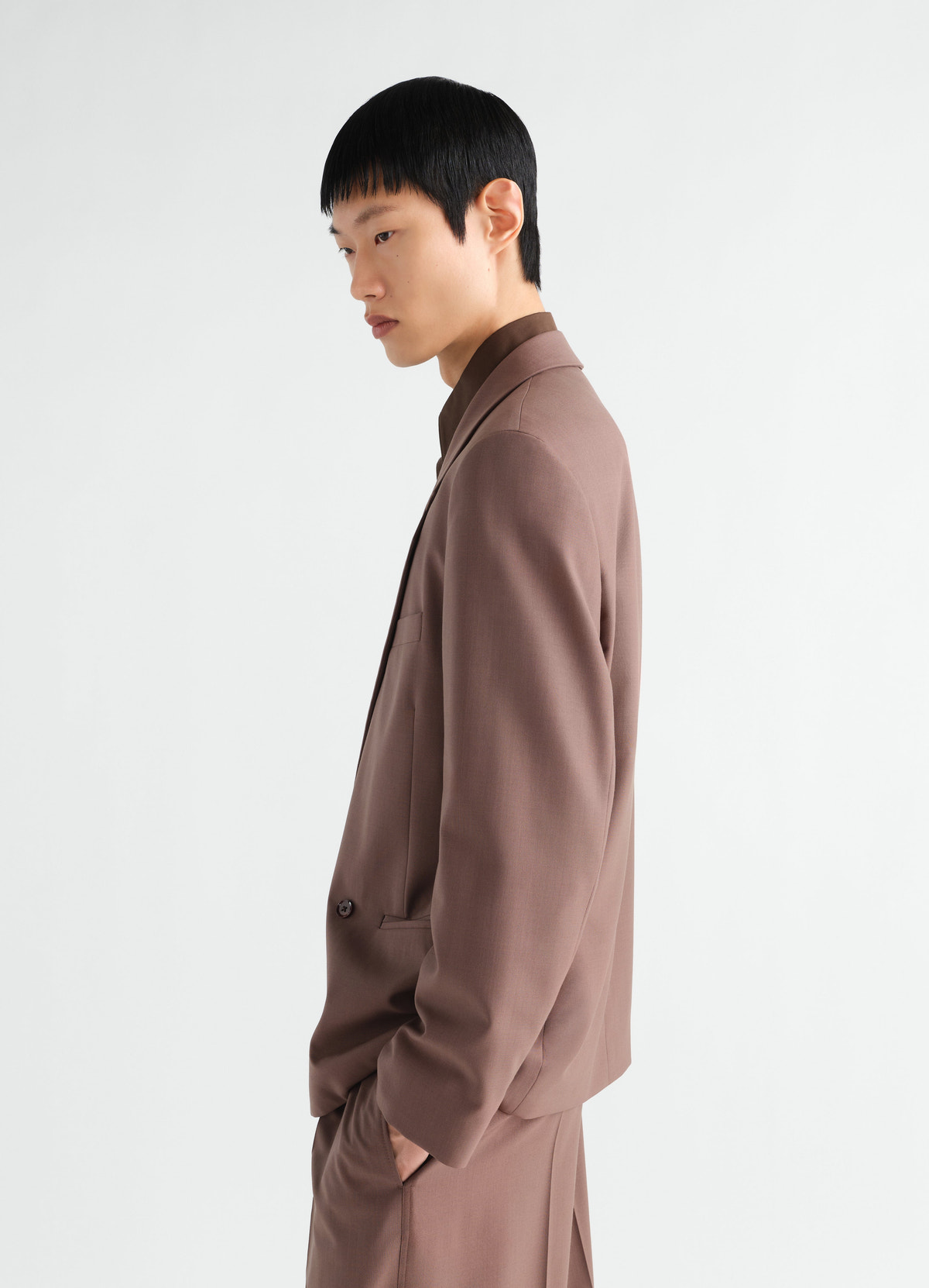 Double-breasted brown wool blend jacket lemaire worn by model side view on plain background