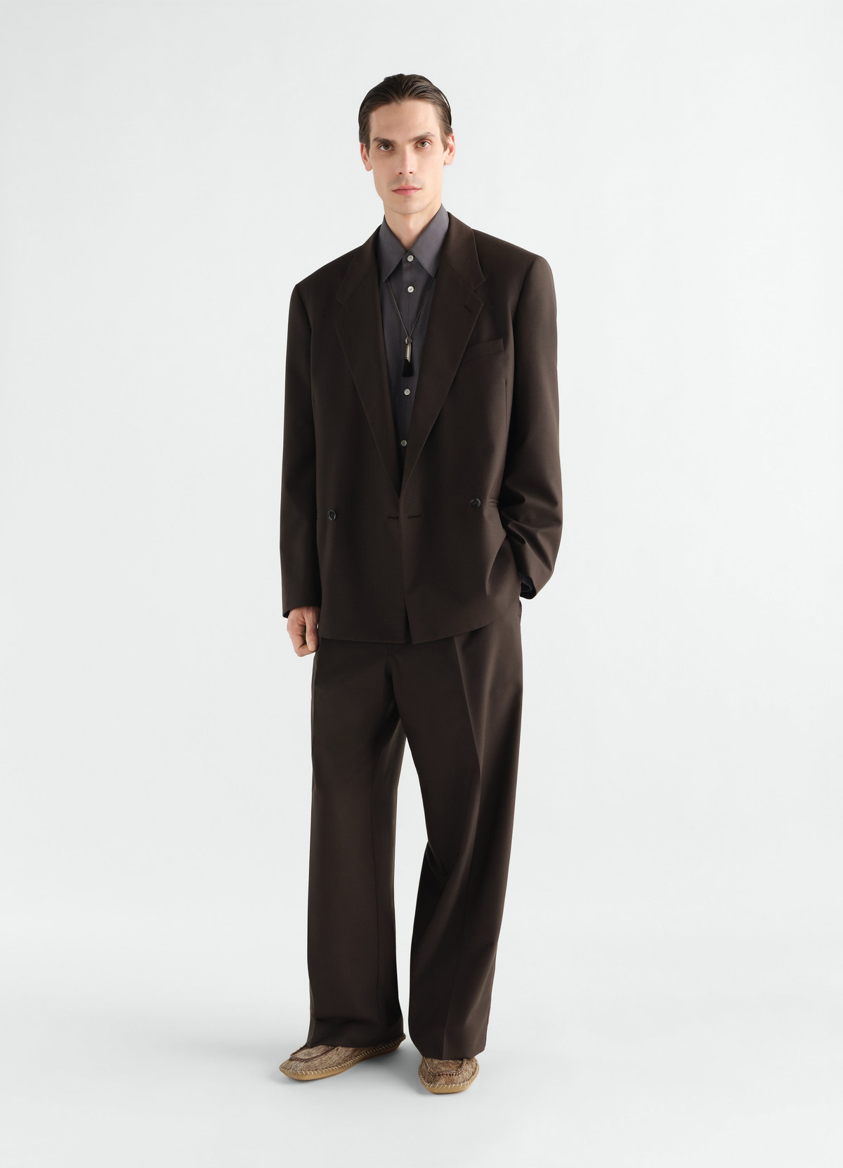 Double-breasted dark brown tropical wool blend jacket by lemaire worn by model front view with matching trousers