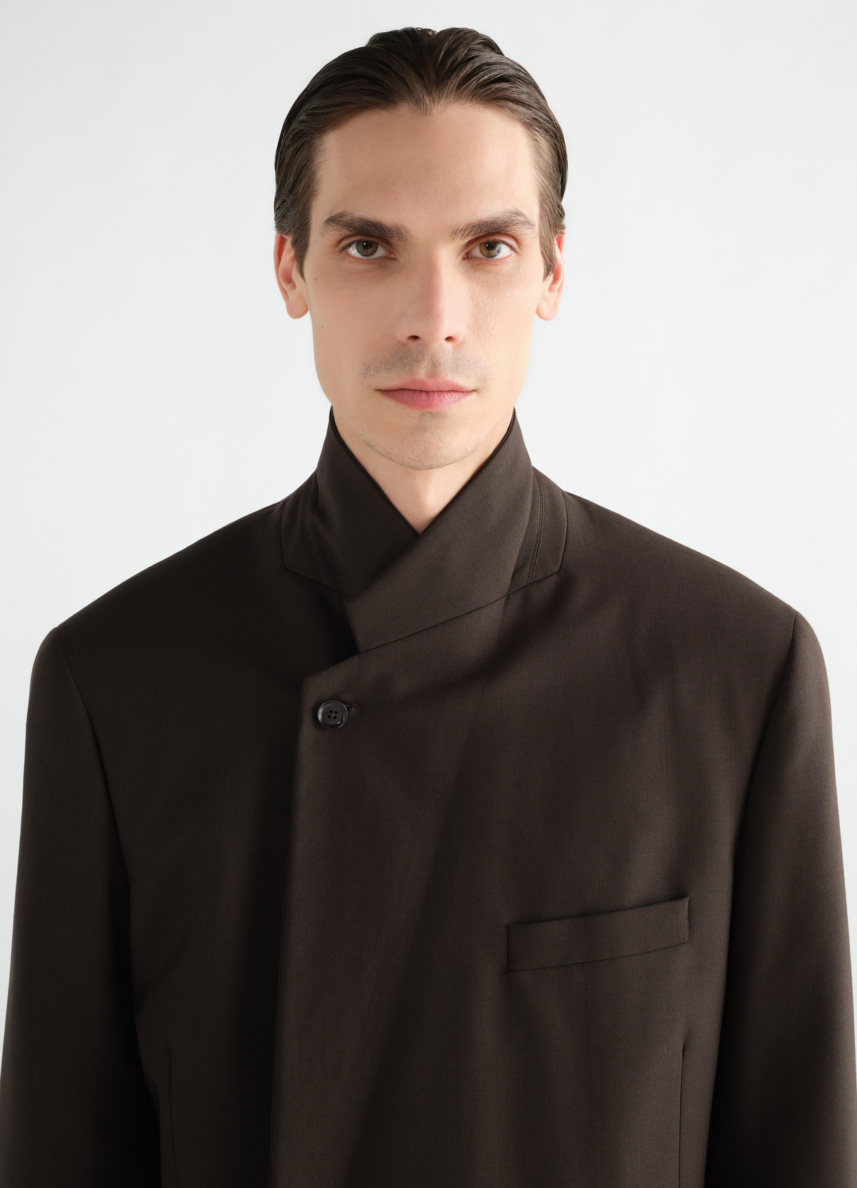 Double-breasted dark brown wool blend jacket lemaire worn by a model front close-up with high collar