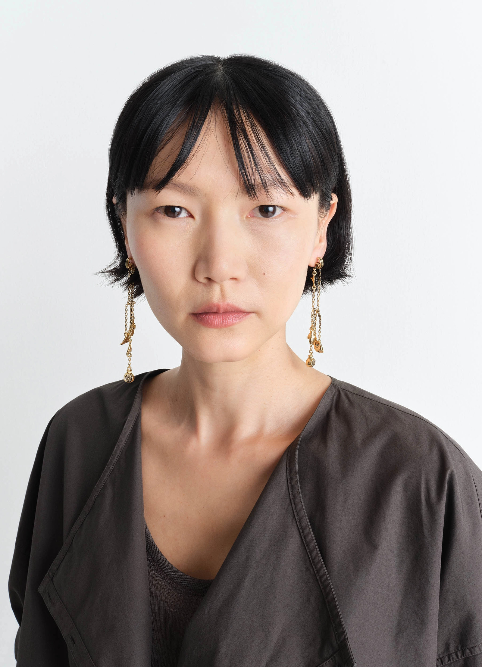 Estampe earrings in aged-effect gilded brass, model shot, side view dangling chain