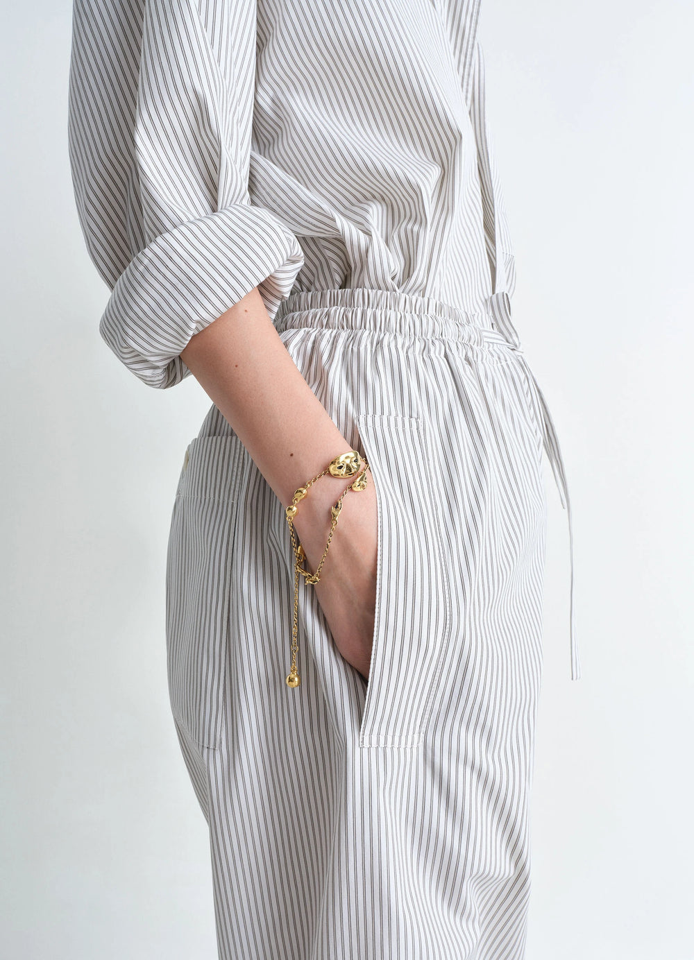 Estampe Bracelet in Aged-effect Gold-plated Brass, model shot, wrist side view layered with striped outfit