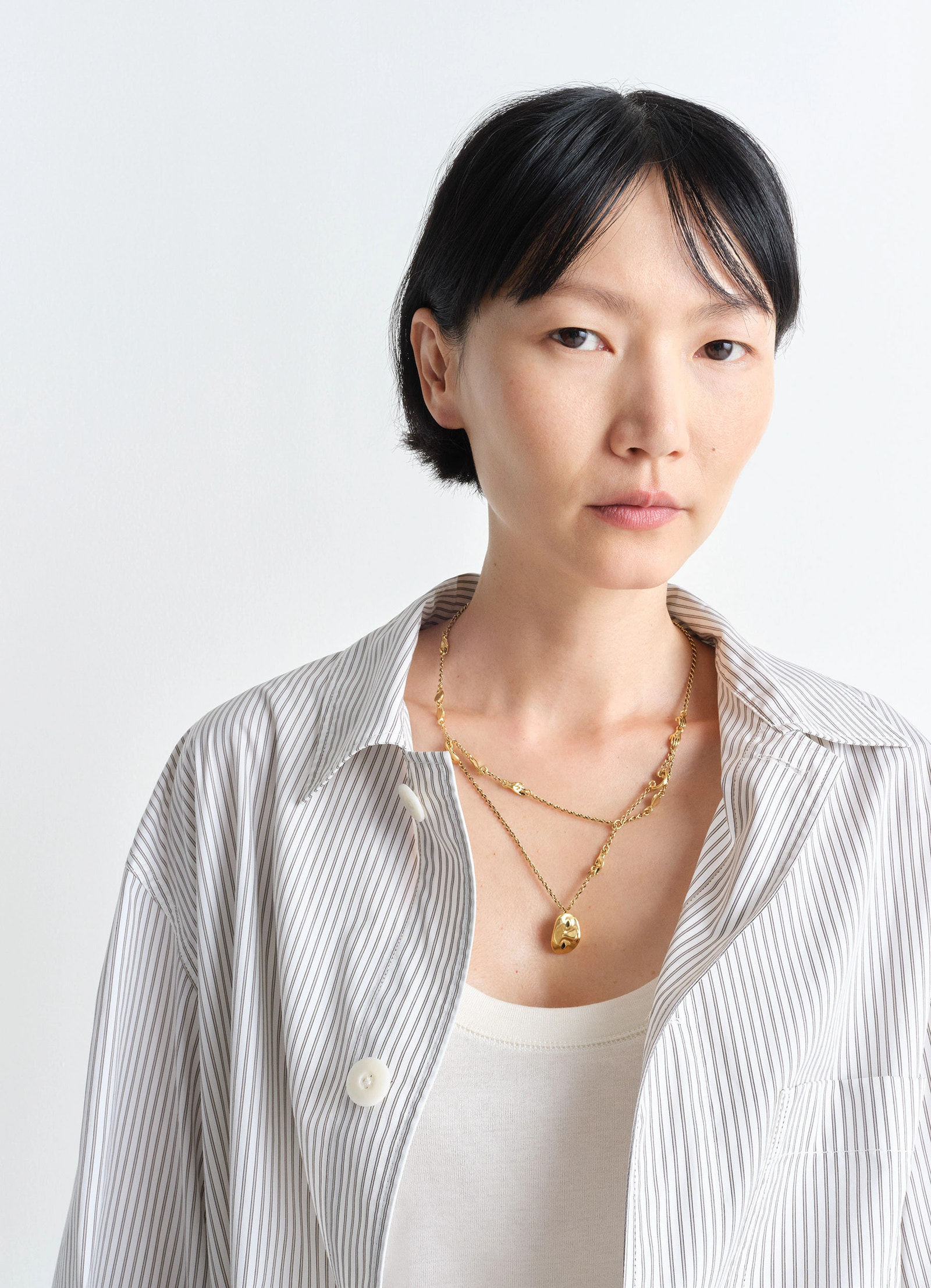 Estampe necklace in aged-effect gilded brass, model shot, close-up view layered with pendant