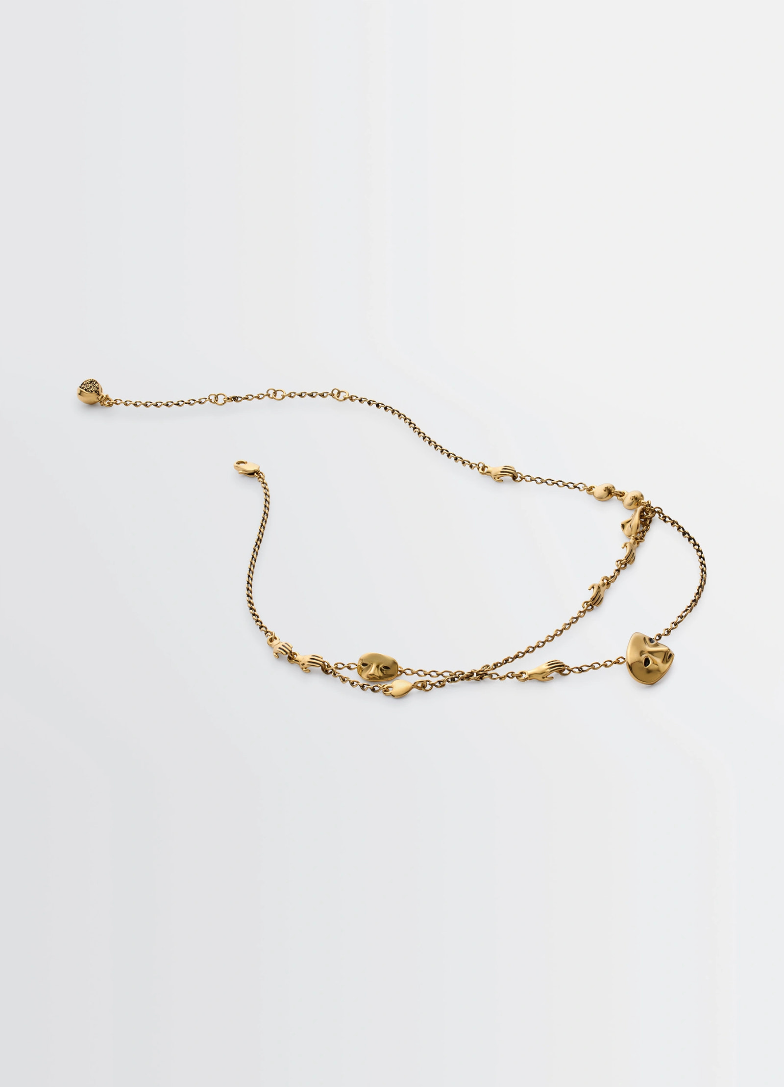 Estampe necklace in aged-effect gilded brass, product shot, top view scattered charm arrangement
