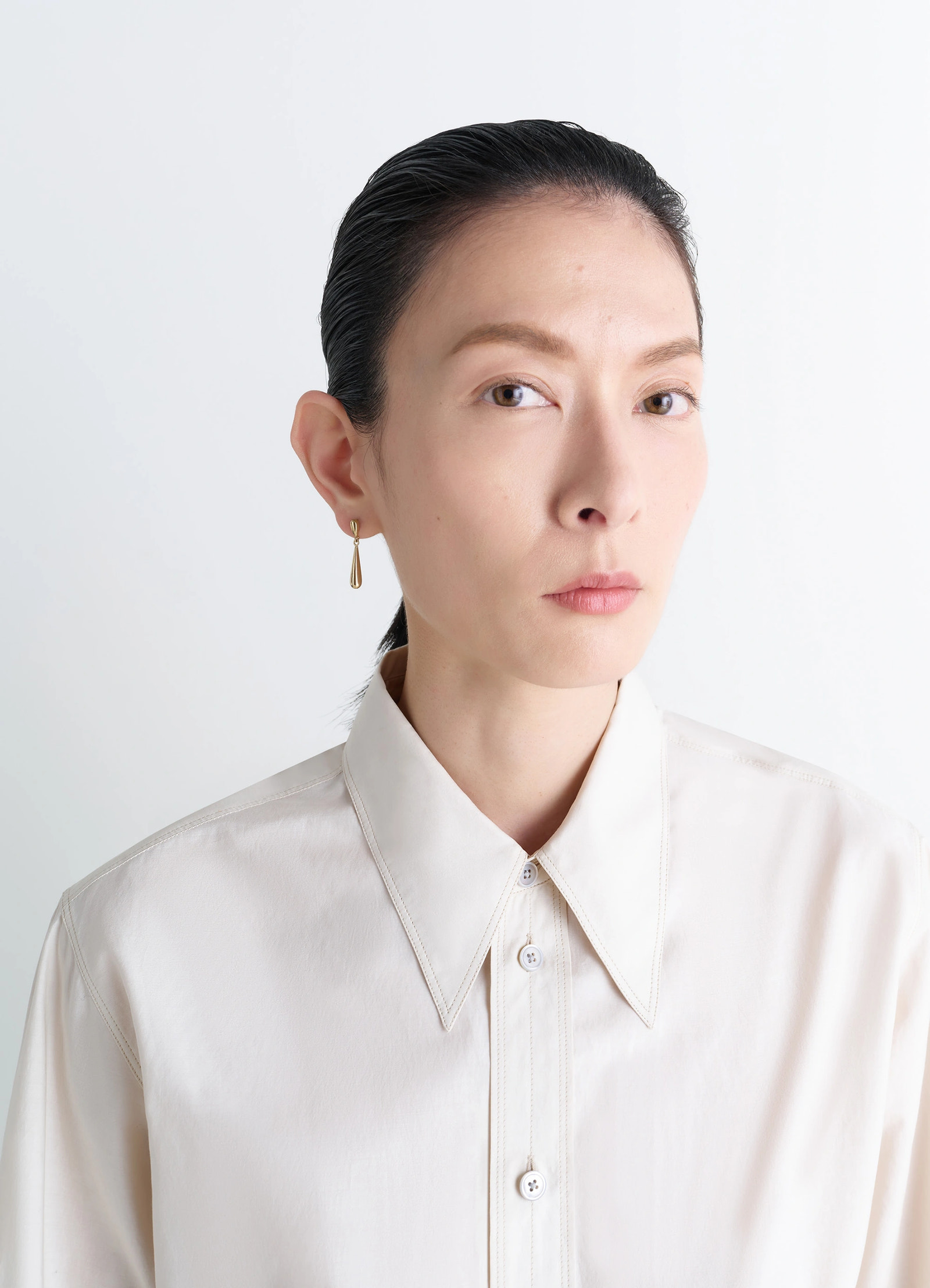 Piercings set in gold-plated silver and resin, model shot, portrait side view drop shape earring design