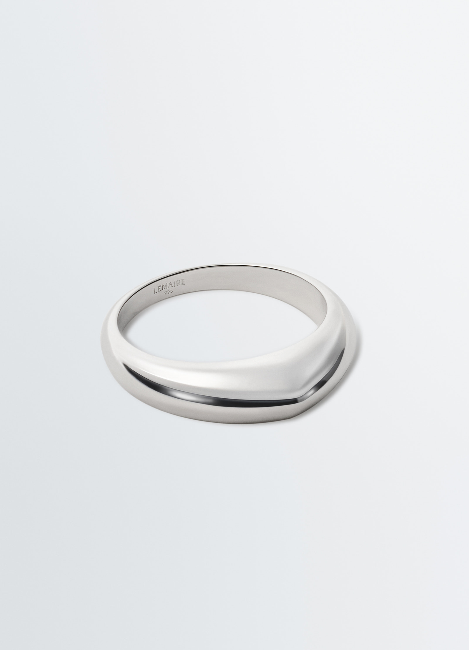 Drop ring in polished silver metal with engraved lemaire logo inside, close-up on plain white background