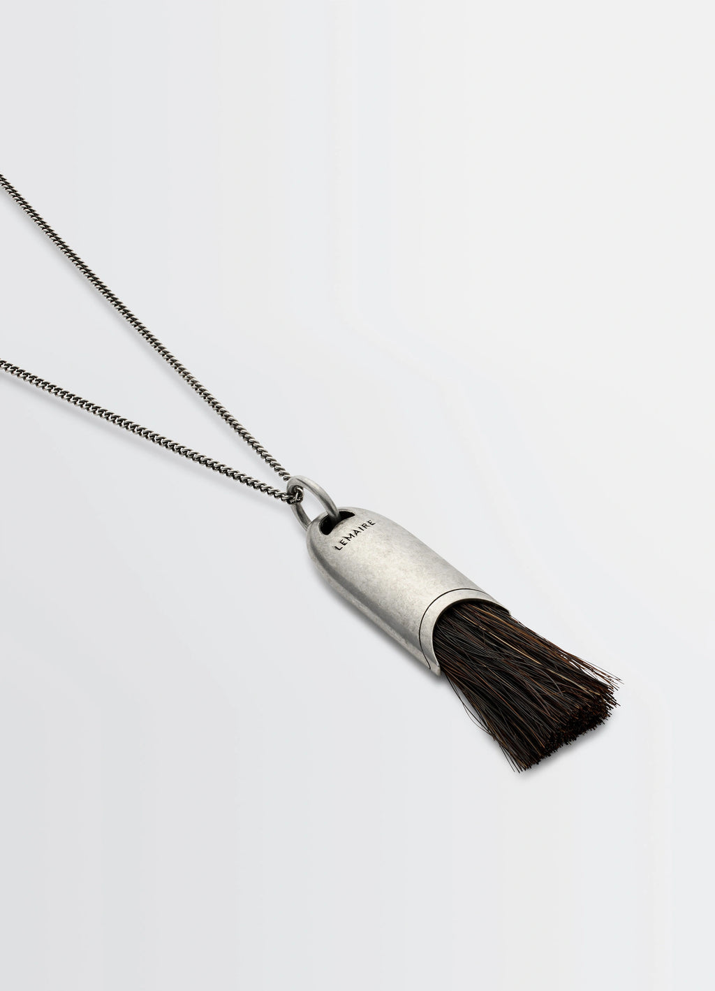 Lemaire Personal Brush Necklace in Silver and Dark Brush, product shot, angled overhead shot textured brush pendant