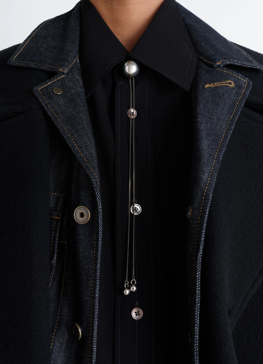Lemaire Rattle Bolo Tie in Silver-plated Brass, model shot, close-up view layered over denim
